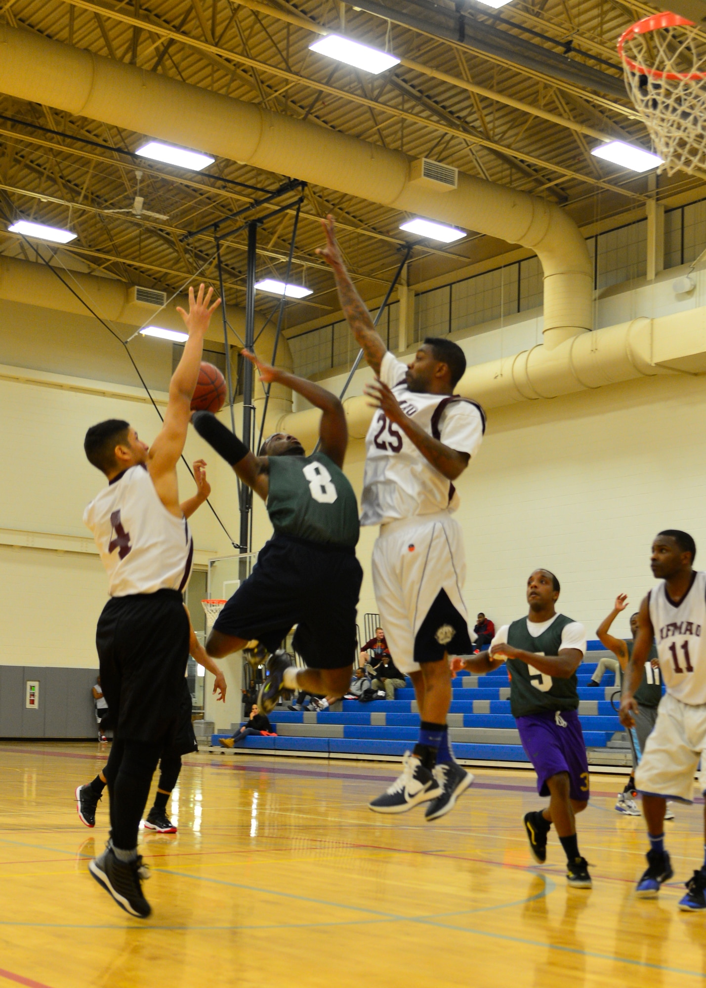 Lateef Shinaba, 512th Airlift Wing point guard, splits two Air Force Mortuary Affairs Operations defenders while going up for a shot Jan. 15, 2015, during an intramural basketball game at the fitness center on Dover Air Force Base, Del. Shinaba was the high scorer for his team and contributed 19 points to the 57-37 victory against AFMAO. (U.S. Air Force photo/Airman 1st Class William Johnson) 