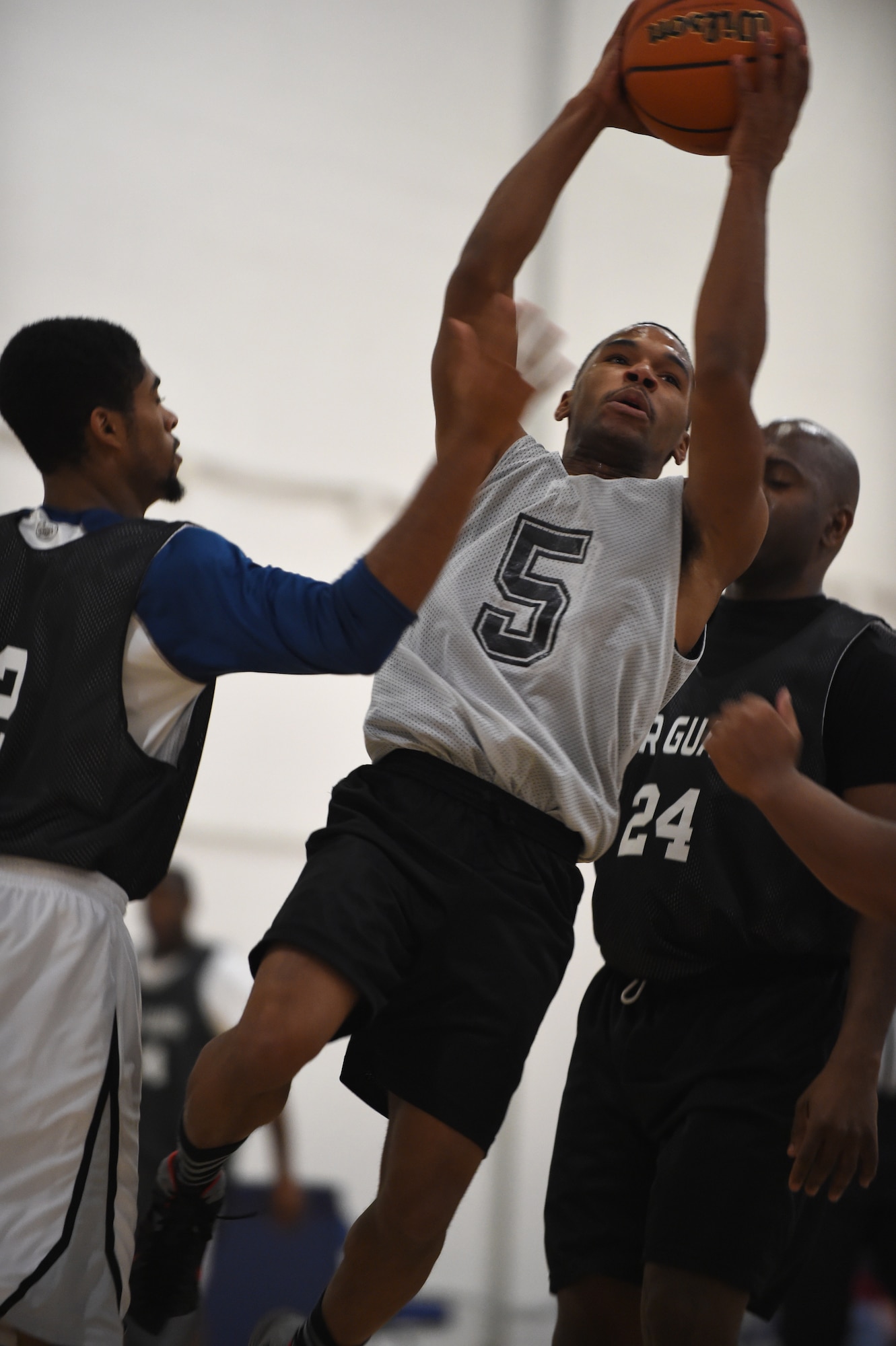 A1C Gemaude Sanders, 89th Communications Squadron point guard, drives past defenders during an intramural game at the West Fitness Center on Joint Base Andrews, Md., Jan. 15, 2015. Sanders made the shot, which helped the 89 CS win over the Air Guard Bureau. (U.S. Air Force photo/Airman 1st Class Philip Bryant)