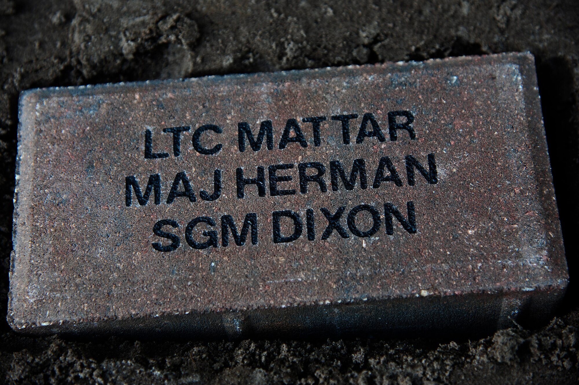 A brick lays in the soil at the 290th Joint Communications Support Squadron’s brick dedication ceremony at MacDill Air Force Base, Fla., Jan. 14, 2015. The brick was placed to honor three fallen Joint Communications Support Element members, Lt. Col. George Mattar, Maj. Ralph Herman, and Sgt. Maj. James Dixon. (U.S. Air Force photo by Senior Airman Vernon L. Fowler Jr./Released)