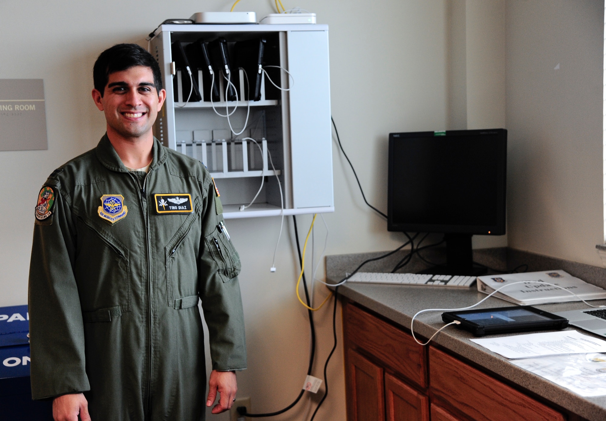 Capt. Valentino Diaz, 91st Air Refueling Squadron chief of standardization and evaluation, poses for a photo in front of the improved electronic-based system at MacDill Air Force Base, Fla., Jan. 12, 2015. The electronic-based system has improved operational efficiency by allowing Airmen to access mission planning papers and inflight publications through an iPad app in order to be ready to fly in shorter time than the paper-based system. (U.S. Air Force photo by Airman 1st Class Danielle Conde/Released)