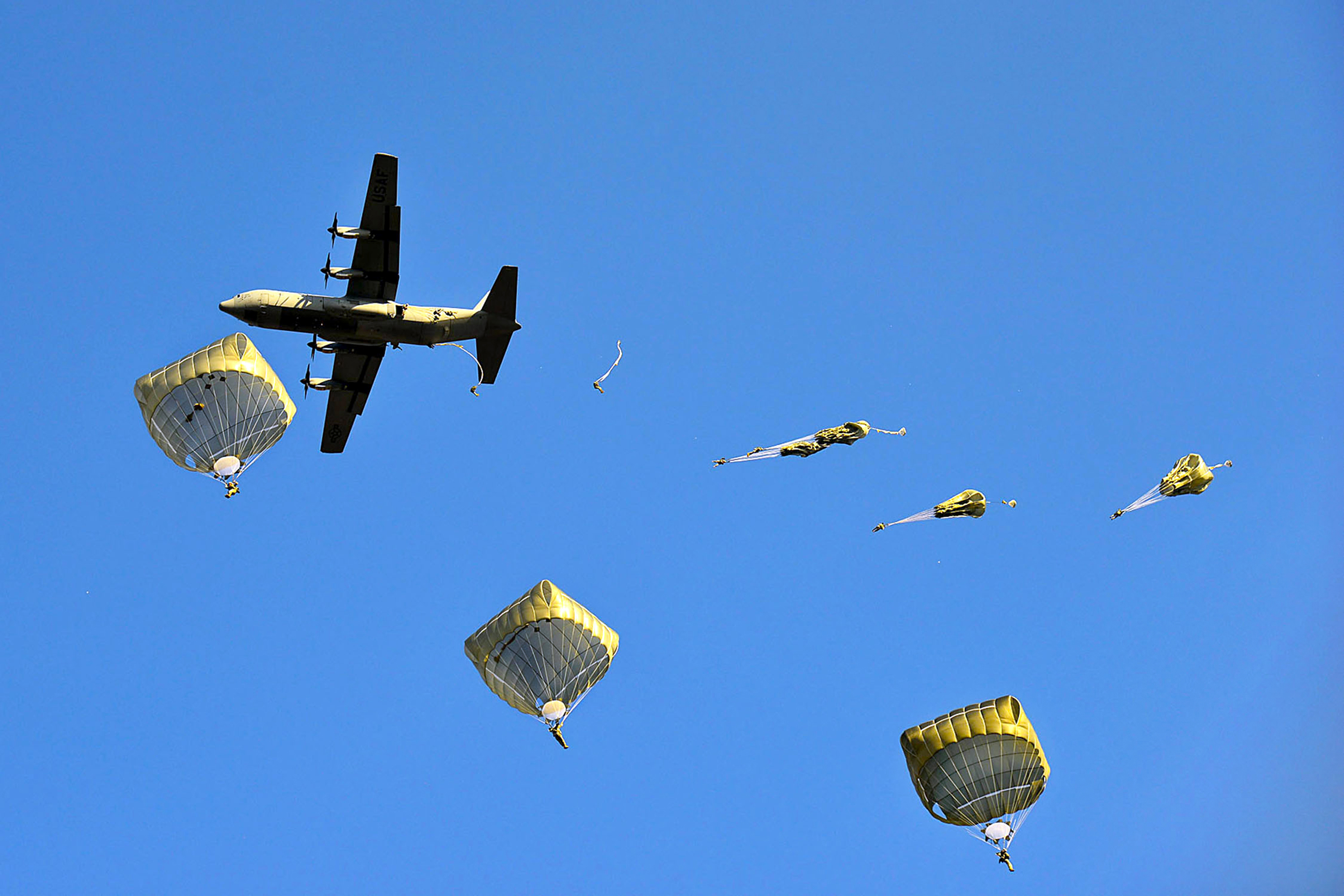 U.S. paratroopers jump out of a C-130 Hercules aircraft over
