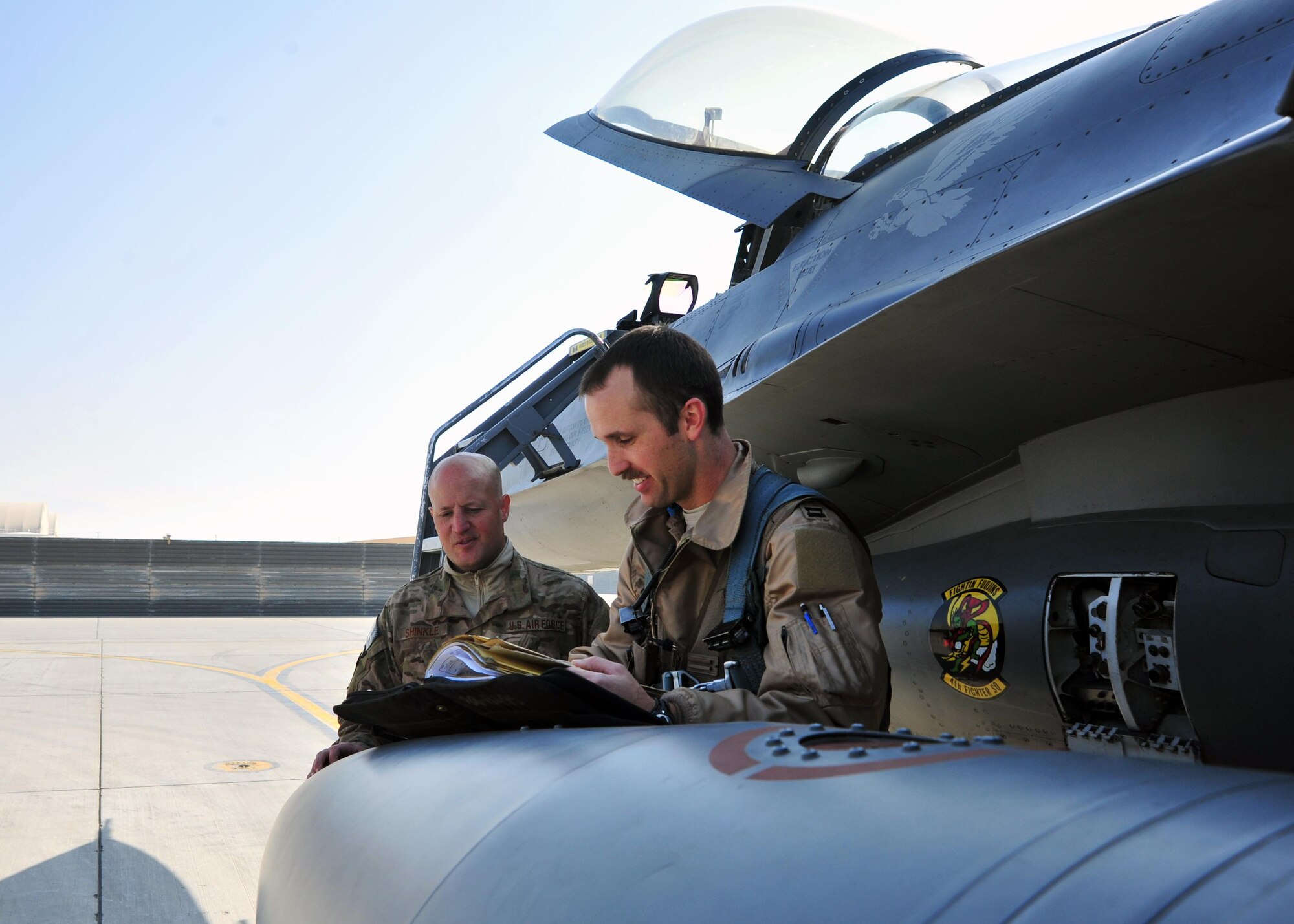 A U.S. Air Force F-16 pilot assigned to the 4th Expeditionary Fighter Squadron, and U.S. Air Force Senior Airman Brandon Shinkle, 455th Expeditionary Aircraft Maintenance Squadron crew chief, review preflight checklists for an F-16 Fighting Falcon in preparation for a mission Jan. 9, 2015 at Bagram Airfield, Afghanistan. The F-16 is a multi-role fighter aircraft that provides air superiority enabling freedom of movement for troops on the ground as well as close air support for troops engaged in combat. It provides a relatively low-cost, high-performance weapon system for the United States and allied nations. (U.S. Air Force photo by Staff Sgt. Whitney Amstutz/released)