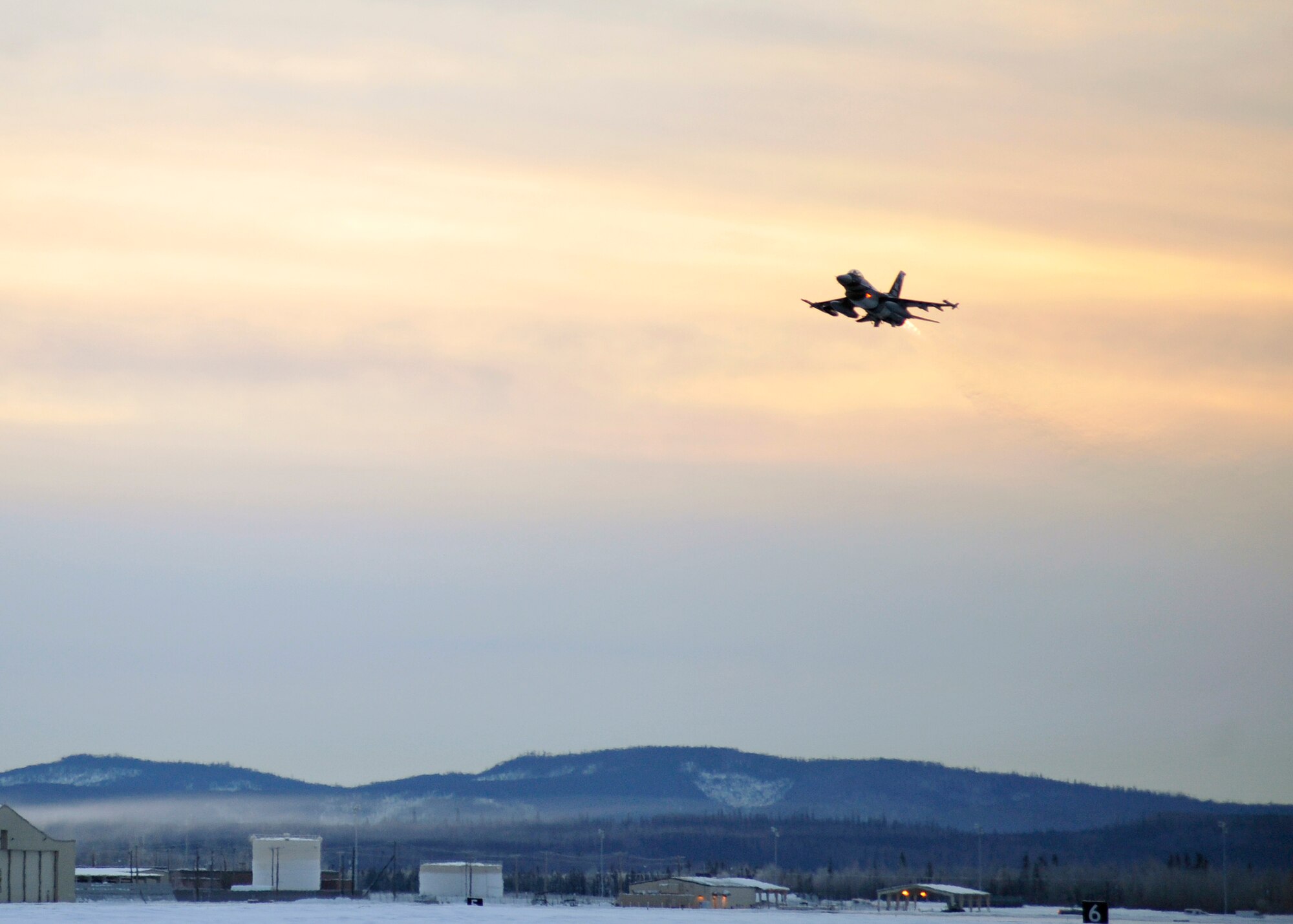 One of 14 U.S. Air Force F-16 Fighting Falcon aircraft with the 18th Aggressor Squadron takes off from Eielson Air Force Base, Alaska, shortly after sunrise Jan. 17, 2015, in transit to Hickam Air Force Base, Hawaii, and Andersen Air Force Base, Guam to participate in the SENTRY ALOHA and COPE NORTH exercises. More than 150 maintainers will keep the Aggressors in the air during the exercises, which are meant to prepare U.S. Airmen, Sailors and Marines along with coalition partners in the Pacific theater of operations for contingency operations if the need arises. (U.S. Air Force photo by Master Sgt. Karen J. Tomasik)