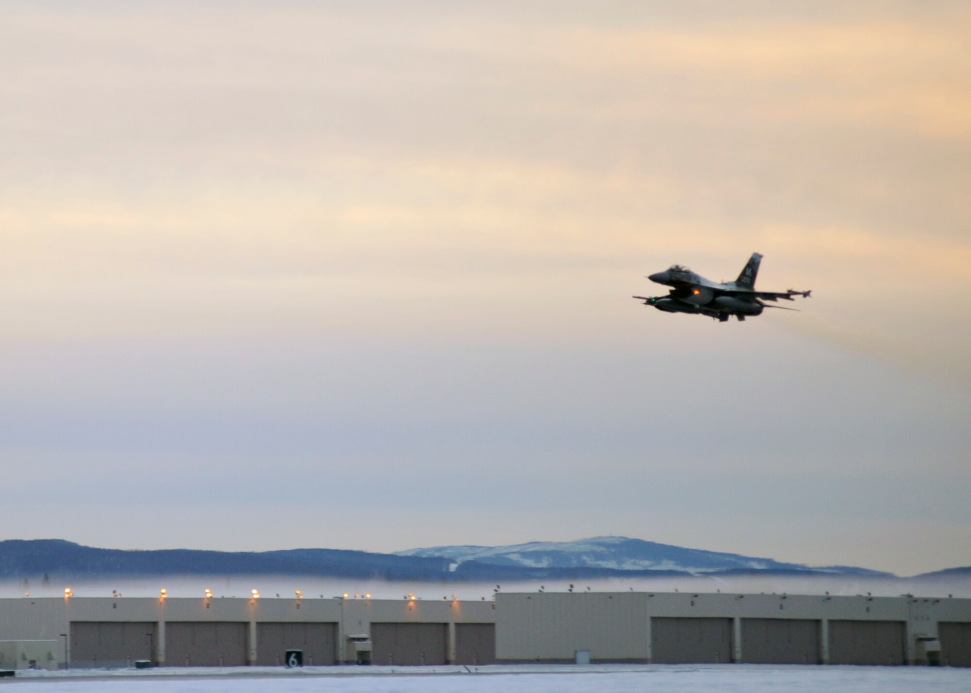 One of 14 U.S. Air Force F-16 Fighting Falcon aircraft with the 18th Aggressor Squadron takes off from Eielson Air Force Base, Alaska, shortly after sunrise Jan. 17, 2015, in transit to Hickam Air Force Base, Hawaii, and Andersen Air Force Base, Guam to participate in the SENTRY ALOHA and COPE NORTH exercises. More than 150 maintainers will keep the Aggressors in the air during the exercises, which are meant to prepare U.S. Airmen, Sailors and Marines along with coalition partners in the Pacific theater of operations for contingency operations if the need arises. (U.S. Air Force photo by Master Sgt. Karen J. Tomasik)