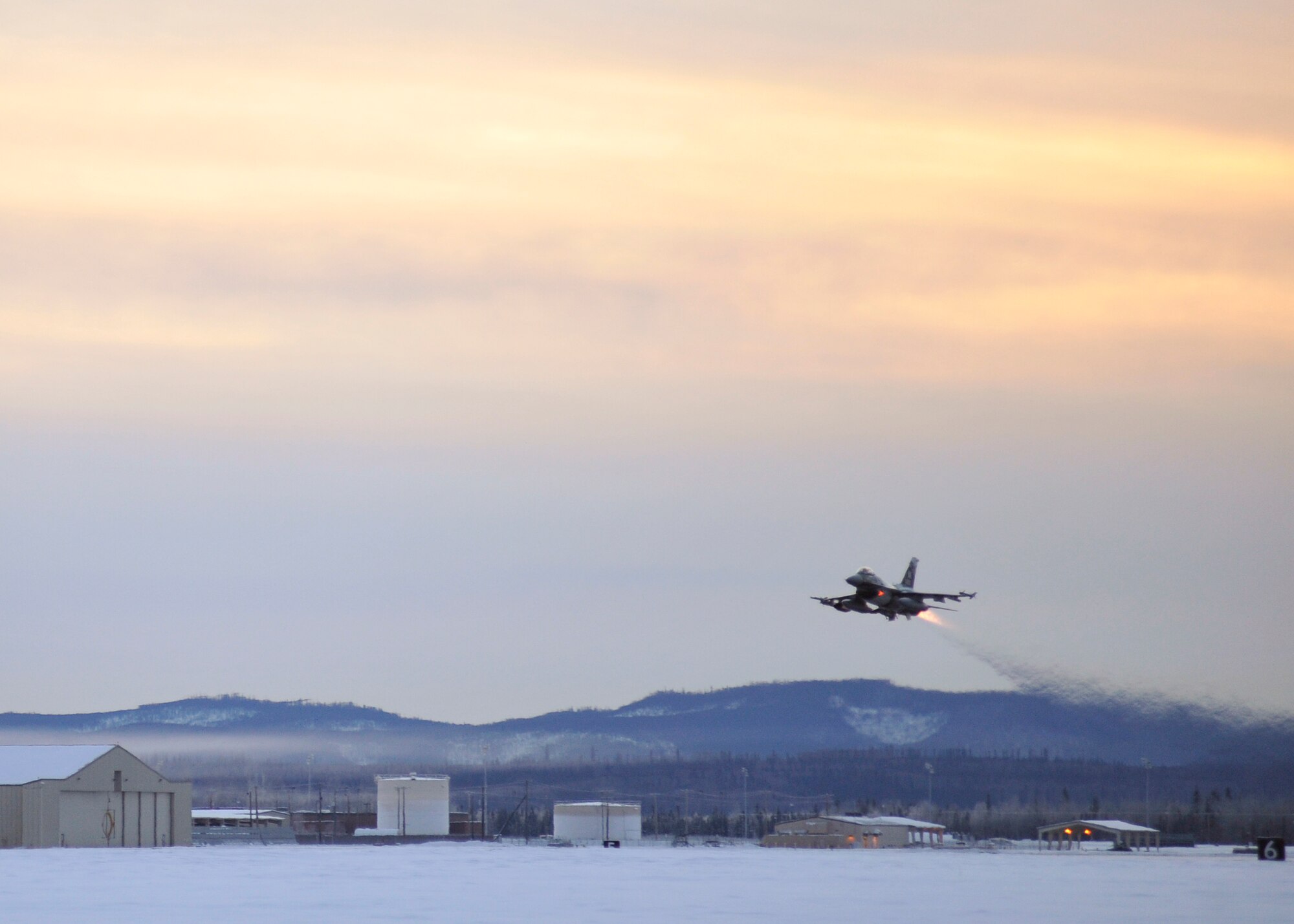 One of 14 U.S. Air Force F-16 Fighting Falcon aircraft with the 18th Aggressor Squadron takes off from Eielson Air Force Base, Alaska, shortly after sunrise Jan. 17, 2015, in transit to Hickam Air Force Base, Hawaii, and Andersen Air Force Base, Guam to participate in the SENTRY ALOHA and COPE NORTH exercises. More than 150 maintainers will keep the Aggressors in the air during the exercises, which are meant to prepare U.S. Airmen, Sailors and Marines along with coalition partners in the Pacific theater of operations for contingency operations if the need arises. (U.S. Air Force photo by Master Sgt. Karen J. Tomasik)