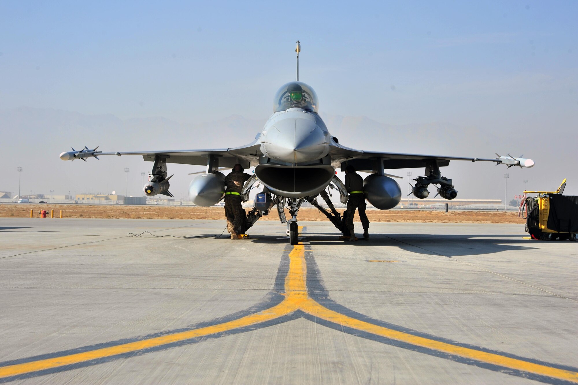 A U.S. Air Force F-16 pilot assigned to the 4th Expeditionary Fighter Squadron, prepares for takeoff while U.S. Air Force Senior Airman Brandon Shinkle, 455th Expeditionary Aircraft Maintenance Squadron crew chief, and U.S. Air Force Senior Airman Alec Cruz, 455 EAMXS, perform final preflight inspections  on an F-16 Fighting Falcon in preparation for a mission Jan. 9, 2015 at Bagram Airfield, Afghanistan. The F-16 is a multi-role fighter aircraft that provides air superiority enabling freedom of movement for troops on the ground as well as close air support for troops engaged in combat. It provides a relatively low-cost, high-performance weapon system for the United States and allied nations. (U.S. Air Force photo by Staff Sgt. Whitney Amstutz/released)