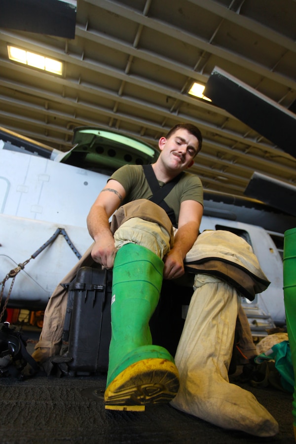 Lance Cpl. Brandon C. Smith, a chemical, biological, radioactive, and nuclear defense specialist with the 24th Marine Expeditionary Unit, puts on a Trellchem level-B training suit during a hazardous materials equipment class aboard the amphibious assault ship USS Iwo Jima (LHD 7), Jan. 15, 2015. The 24th MEU is embarked on the ships of the Iwo Jima Amphibious Ready Group and deployed to maintain regional security in the U.S. 5th Fleet area of operations. (U.S. Marine Corps photo by Lance Cpl. Austin A. Lewis)