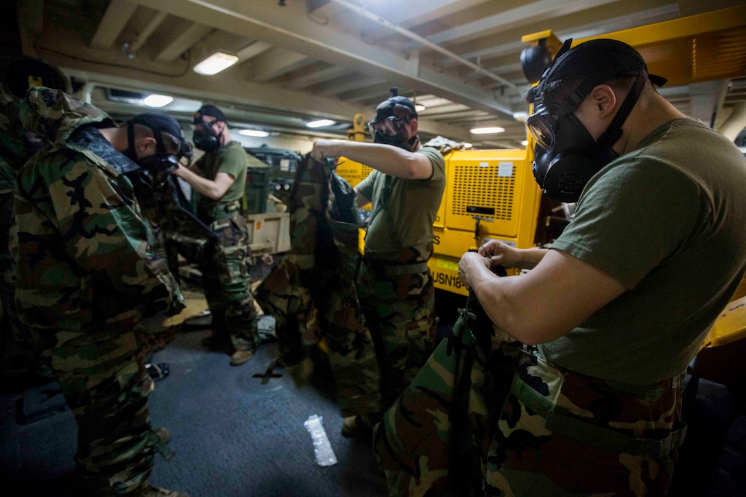 Marines with Combat Logistics Battalion 24, 24th Marine Expeditionary Unit, get into Mission Oriented Protective Posture (MOPP) suits during a MOPP proficiency training aboard the amphibious transport dock ship USS New York (LPD 21), at sea, Jan. 13, 2015. The 24th MEU is embarked on the ships of the Iwo Jima Amphibious Ready Group and deployed to maintain regional security in the U.S. 5th Fleet area of operations. (U.S. Marine Corps photo by Cpl. Todd F. Michalek)