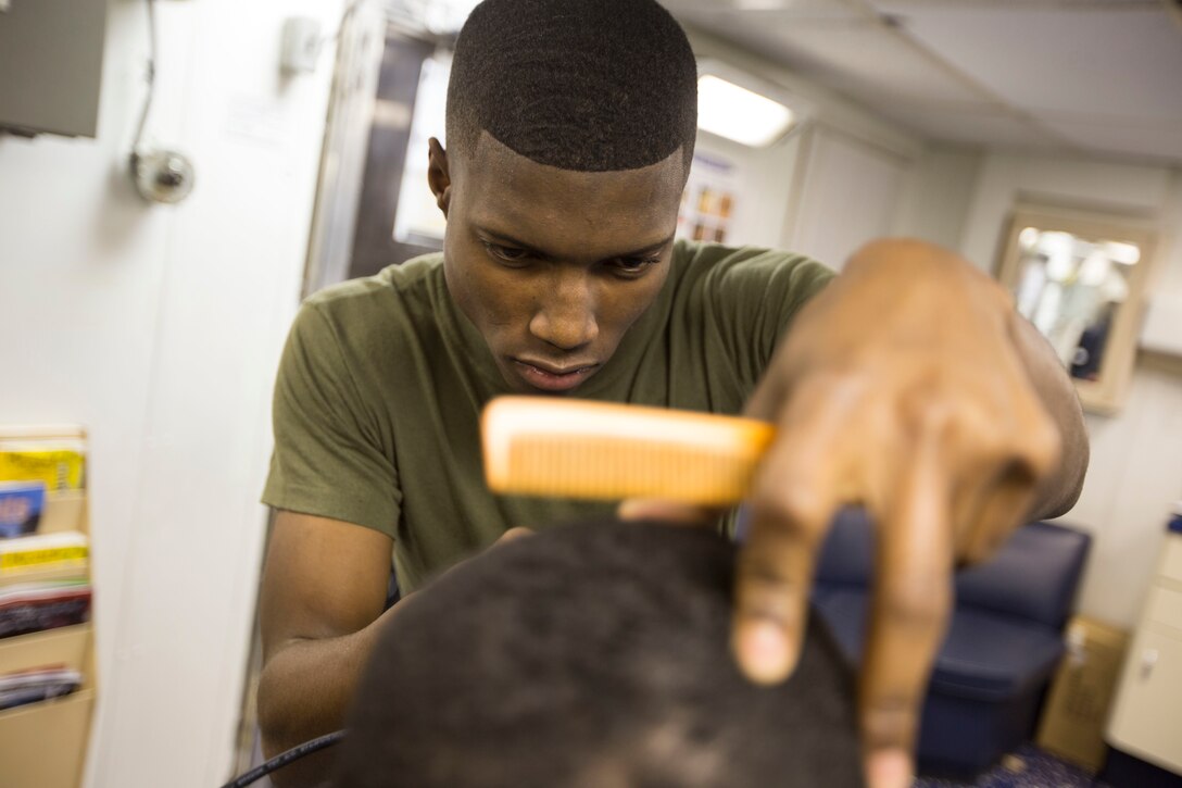 Cpl. Malik S. RolandPickens, a warehouse clerk with Combat Logistics Battalion 24, 24th Marine Expeditionary Unit, cuts a Marines hair aboard the USS Fort McHenry, at sea, Jan. 6, 2015. (U.S. Marine Corps photo by Sgt. Devin Nichols)