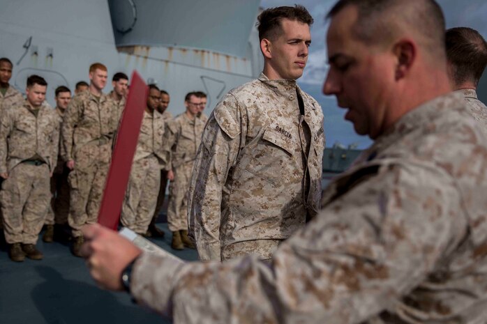 Aldo Garcia, center, a field wireman with Combat Logistics Battalion 24, 24th Marine Expeditionary Unit, stands in formation while Gunnery Sgt. Timothy stone reads his promotion warrant aboard the USS New York, at sea, Jan. 10, 2015. The 24th MEU and Iwo Jima Amphibious Ready Group are conducting naval operations in the U.S. 6th Fleet of operations in support of U.S. national security interests in Europe. (U.S. Marine Corps photo by Cpl. Todd F. Michalek)