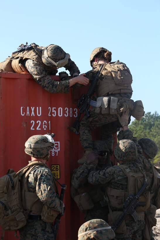 Marines with Engineer Platoon, Headquarters and Service Company, Ground Combat Element Integrated Task Force, assist each other in climbing over a storage container during a field training exercise at Engineer Training Area 2 aboard Marine Corps Base Camp Lejeune, North Carolina, Jan. 16, 2015. From October 2014 to July 2015, the GCEITF will conduct individual and collective level skills training in designated ground combat arms occupational specialties in order to facilitate the standards based assessment of the physical performance of Marines in a simulated operating environment performing specific ground combat arms tasks. (U.S. Marine Corps photo by Cpl. Paul S. Martinez/Released)