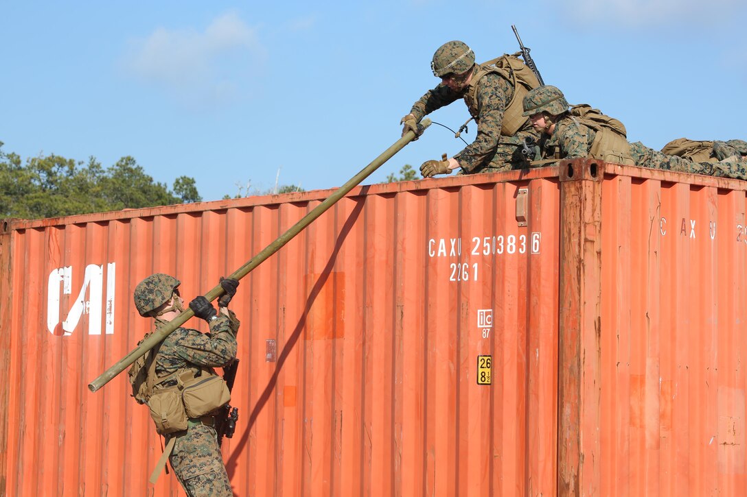 Cpl. Jordan M. Yearsley, left, combat engineer, Engineer Platoon, Headquarters and Service Company, Ground Combat Element Integrated Task Force, and Lance Cpl. Marshal P. Thompson, upper right, combat engineer, Engineer Platoon, H&S Company, GCEITF, transport an M1A2 Bangalore over an storage container during a field training exercise at Engineer Training Area 2 aboard Marine Corps Base Camp Lejeune, North Carolina, Jan. 16, 2015. From October 2014 to July 2015, the GCEITF will conduct individual and collective level skills training in designated ground combat arms occupational specialties in order to facilitate the standards based assessment of the physical performance of Marines in a simulated operating environment performing specific ground combat arms tasks. (U.S. Marine Corps photo by Cpl. Paul S. Martinez/Released)
