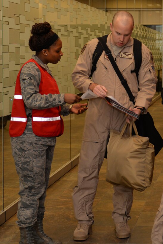 Senior Airman Wintera Jones, 28th Force Support Squadron installation readiness technician, verifies paperwork for 1st Lt. Matthew Shields, 34th Bomb Squadron weapons systems officer, in the Deployment Center at Ellsworth Air Force Base, S.D., Jan. 20, 2015. Ellsworth deployers will take the baton from the 9th Bomb Squadron, Dyess Air Force Base, Texas, who have been deployed since the summer of 2014. (U.S. Air Force photo by Airman 1st Class Rebecca Imwalle/Released)