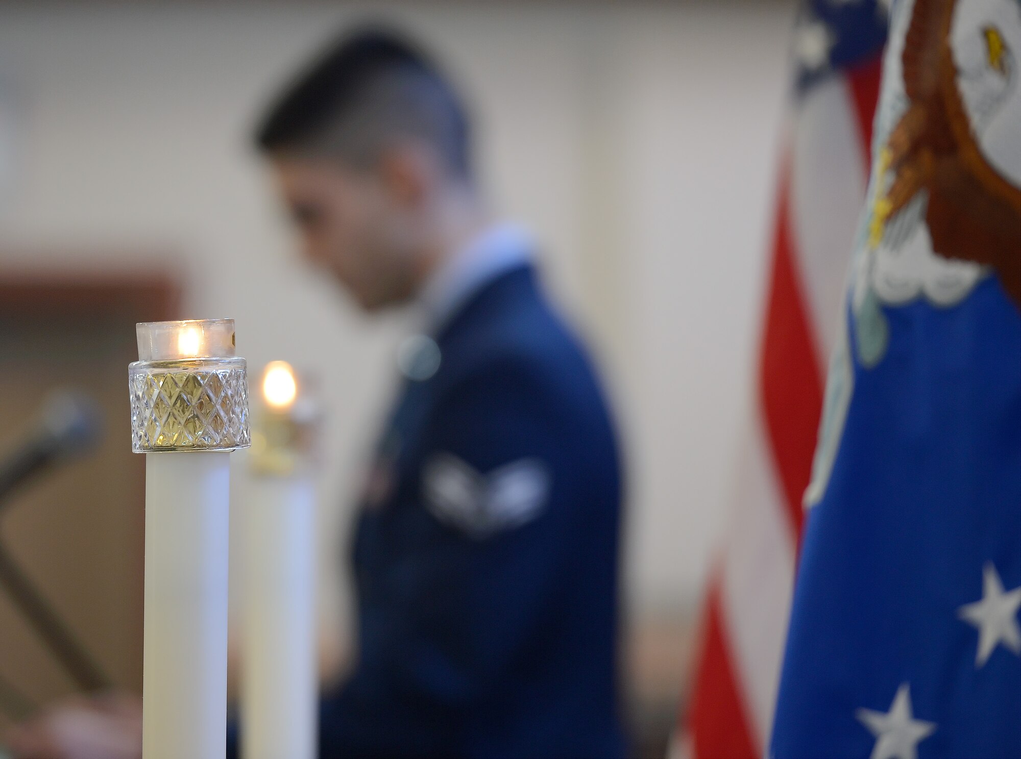 Burning candles along with United States Air Force and American flags in the foreground help to frame Senior Airman  Mateen M. Ansary, 436th Logistics Readiness Squadron, as he speaks from the Dover Air Force Base Chapel podium during the Dr. Martin Luther King, Jr. Day Commemoration Service on Jan. 15, 2015. Ansary delivered a Muslim scripture reading. (U.S. Air Force photo/Greg L. Davis)