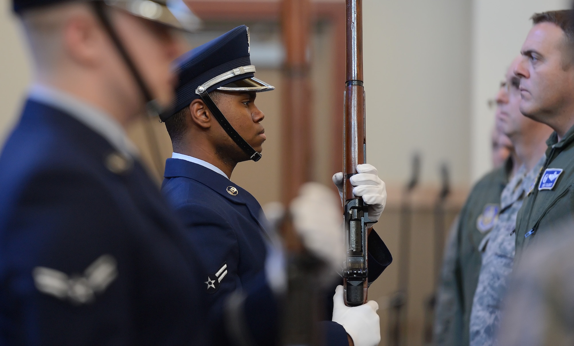 Members of the Dover Air Force Base Honor Guard stand with ceremonial rifles at the ready as the American and Air Force flags are placed in their stands during the opening ceremony for the Dr. Martin Luther King Jr. Day Commemoration Service held at the Dover Air Force Base, Del. main chapel on Jan. 15, 2015. Due to close-quarters inside the chapel the Honor Guard members are standing almost directly in front of gathered attendees to the right.  (U.S. Air Force photo/Greg L. Davis)