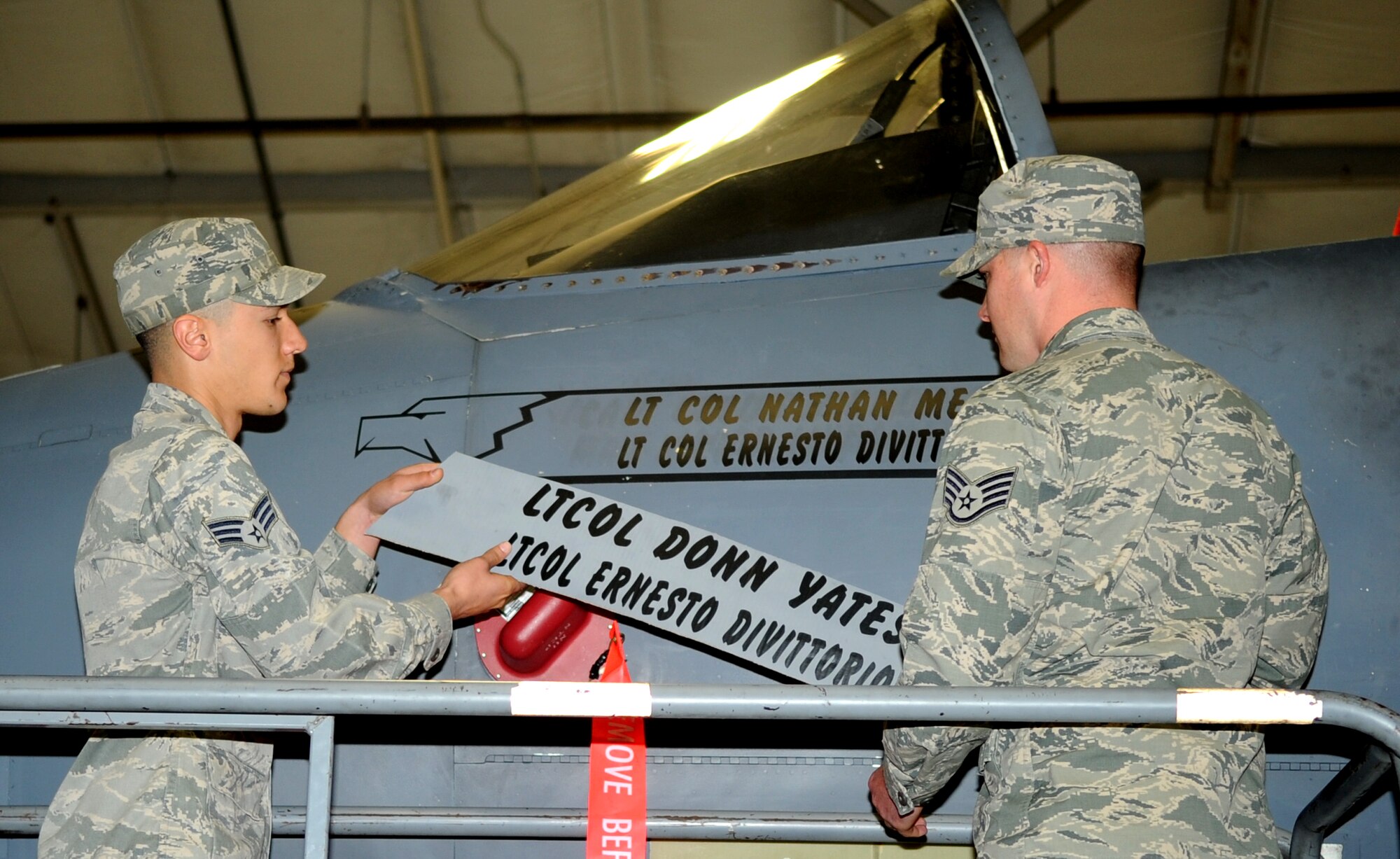 Senior Airman Nicholas Landi, 4th Aircraft Maintenance Squadron, and Staff Sgt. Adam Kipper, 334th Aircraft Maintenance Unit, reveal the 334th Fighter Squadron’s incoming commander’s name, Lt. Col. Nathan Mead, on an F-15E Strike Eagle during a change of command ceremony at Seymour Johnson Air Force Base, North Carolina, Jan. 16, 2015. (U.S. Air Force photo/Senior Airman Ashley J. Thum)