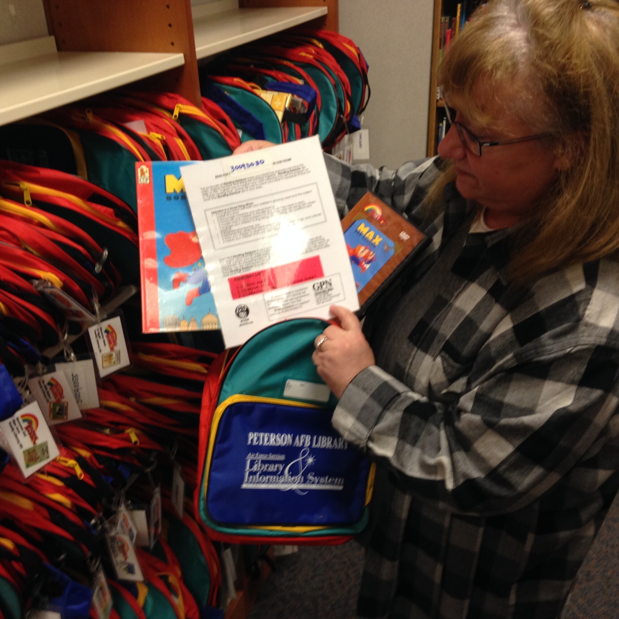 PETERSON AIR FORCE BASE, Colo. -- Peterson library director Kathy Kucharski shows what is inside of the literacy kits available for children at the library. Each kit consists of a backpack, a Reading Rainbow book or DVD and related activity sheets. (U.S. Air Force photo by Dave Smith)