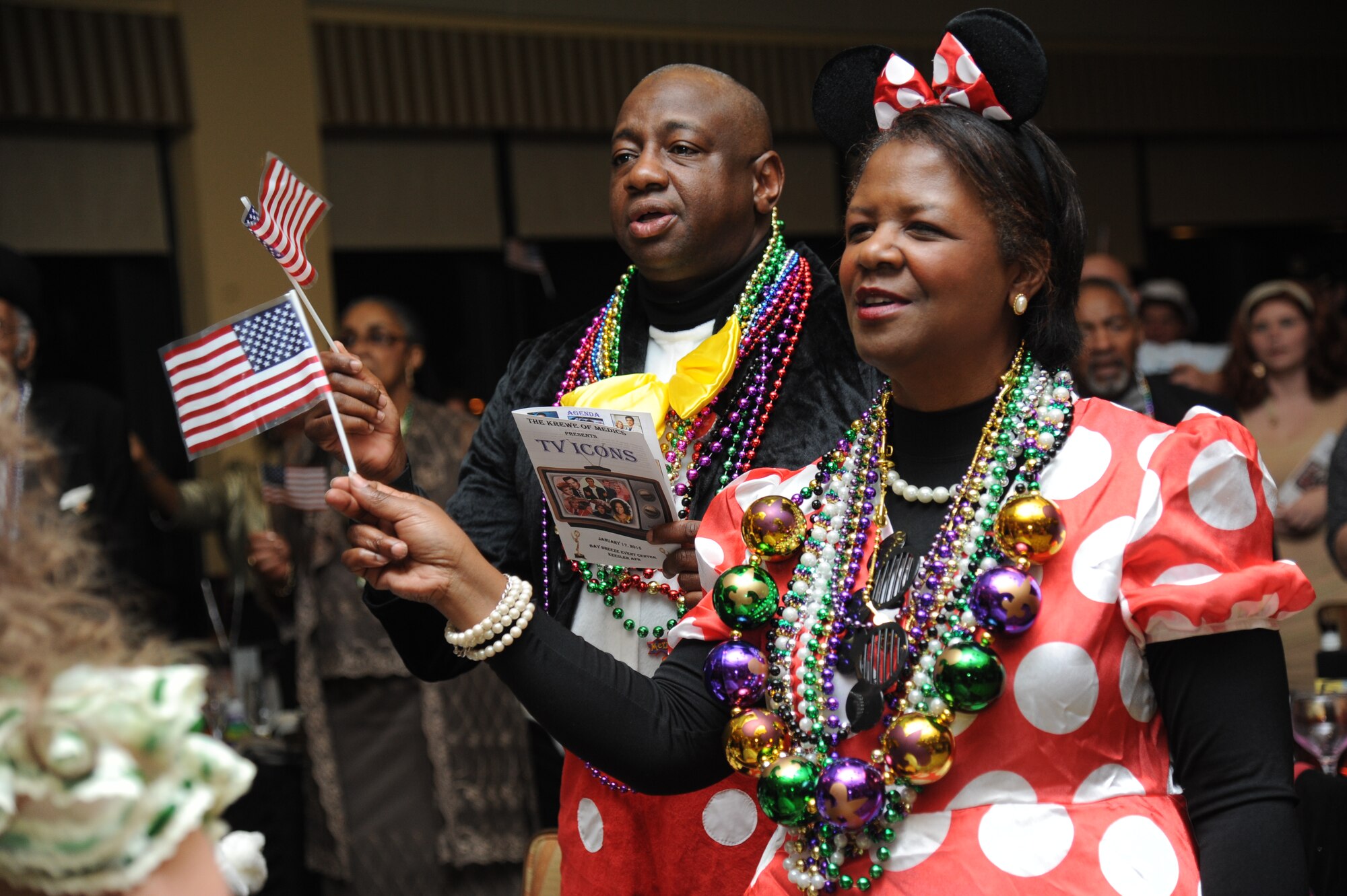 Maj. Gen. Mark Brown, 2nd Air Force commander and his wife, wave the American Flag as they participate in the singing of, “Proud To Be An American,” during the Keesler Medical Center’s 27th annual Krewe of Medics Mardi Gras Ball Jan. 17, 2015, at the Bay Breeze Event Center, Keesler Air Force Base, Miss.  The Krewe of Medics hosts a ball every year to give military personnel assigned to the Keesler Medical Center a taste of the South and an opportunity to experience a traditional Mardi Gras.  The theme of this year's ball was TV Icons. Maj. Marlon Muthuveeran, 81st Medical Support Squadron medical readiness flight commander was crowned King and Sarah Jacobs, Krewe of Medic member, was crowned Queen.  (U.S. Air Force photo by Kemberly Groue)