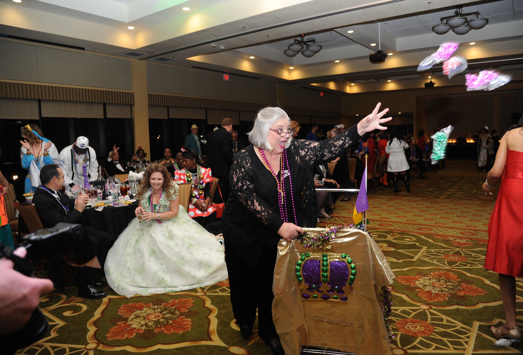 Kay Hymel, former Krewe of Medics queen, tosses beads into the crowd during the Keesler Medical Center’s 27th annual Krewe of Medics Mardi Gras Ball Jan. 17, 2015, at the Bay Breeze Event Center, Keesler Air Force Base, Miss.  The Krewe of Medics hosts a ball every year to give military personnel assigned to the Keesler Medical Center a taste of the South and an opportunity to experience a traditional Mardi Gras.  The theme of this year's ball was TV Icons. (U.S. Air Force photo by Kemberly Groue)