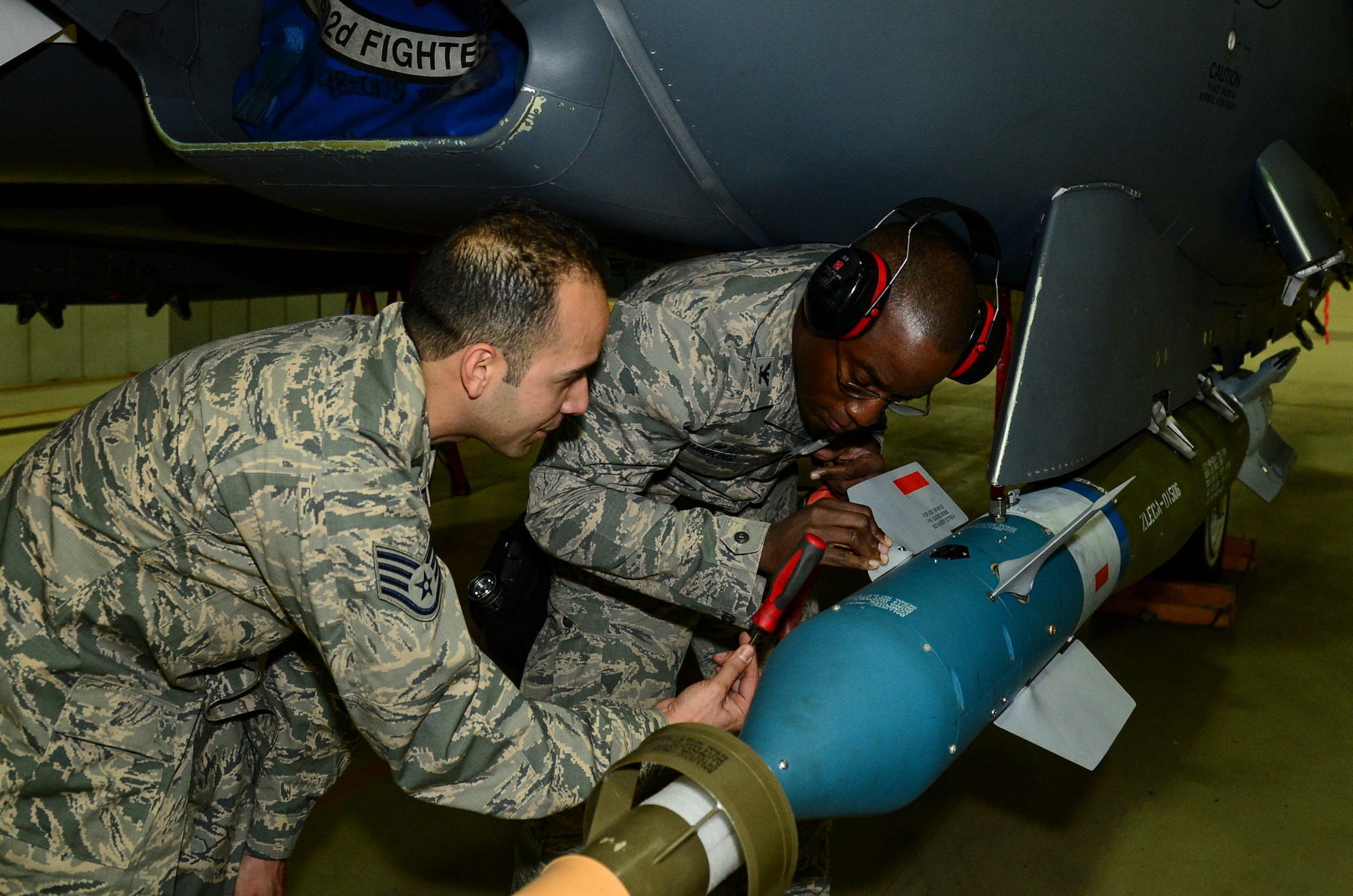 Staff Sgt. Christian Martinez-Negron, 48th Maintenance Group squadron lead crew team chief, hands a tool to Col. Stacey Hawkins, 10th Air Base Wing commander, to finish loading a bomb during an Installation Excellence Selection Board visit on Royal Air Force Lakenheath, England, Jan. 15, 2015. The IESB visited RAF Lakenheath to determine the winner of the Commander in Chief’s Annual Award for Installation Excellence. (U.S. Air Force photo by Airman 1st Class Erin R. Babis/Released)