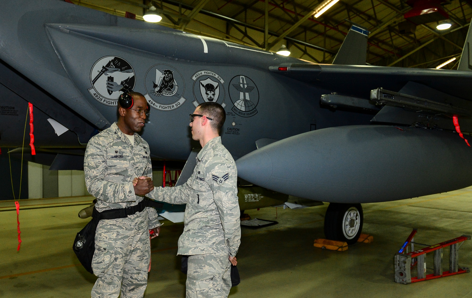 Col. Stacey Hawkins, 10th Air Base Wing commander, shakes hands with Senior Airman Anthony Feret, 48th Maintenance Group aircraft armament systems journeyman, after a load crew demonstration during an Installation Excellence Selection Board visit on Royal Air Force Lakenheath, England, Jan. 15, 2015. RAF Lakenheath and Joint base Andrews were recognized as the top bases in the U.S. Air Force. (U.S. Air Force photo by Airman 1st Class Erin R. Babis/Released)