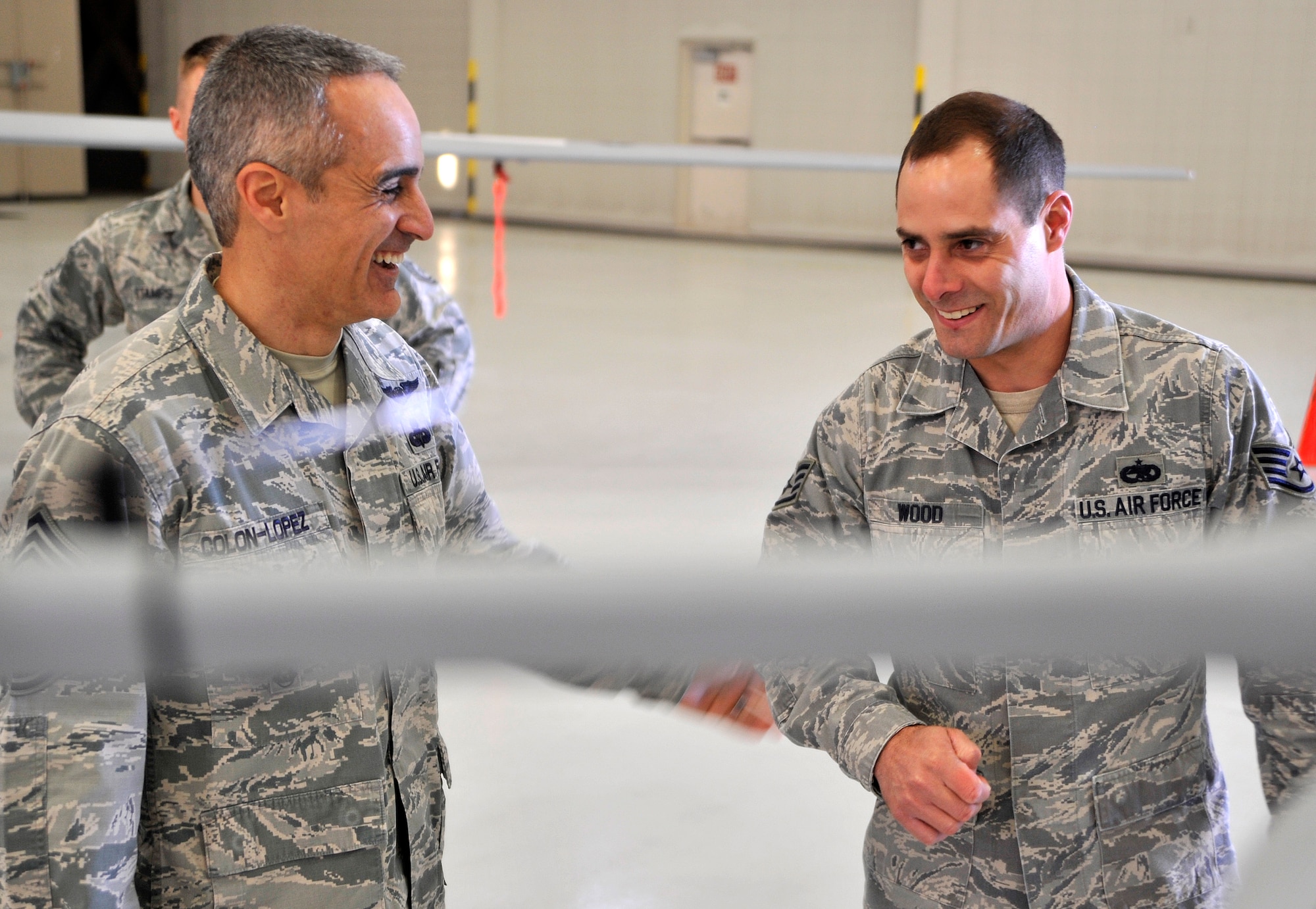 Chief Master Sgt. Ramon Colon-Lopez, U.S. Air Forces Central Command command chief, left, laughs with Staff Sgt. Nathan Wood, 432nd Aircraft Maintenance Squadron Avionics supervisor, during a visit Jan. 15, 2015, to Creech Air Force Base, Nevada. During his visit, the chief stressed to Airmen that no matter what they do or how far the area of responsibility is, they’re making a difference, 24/7, 365. (U.S. Air Force photo by Airman 1st Class Christian Clausen/Released)