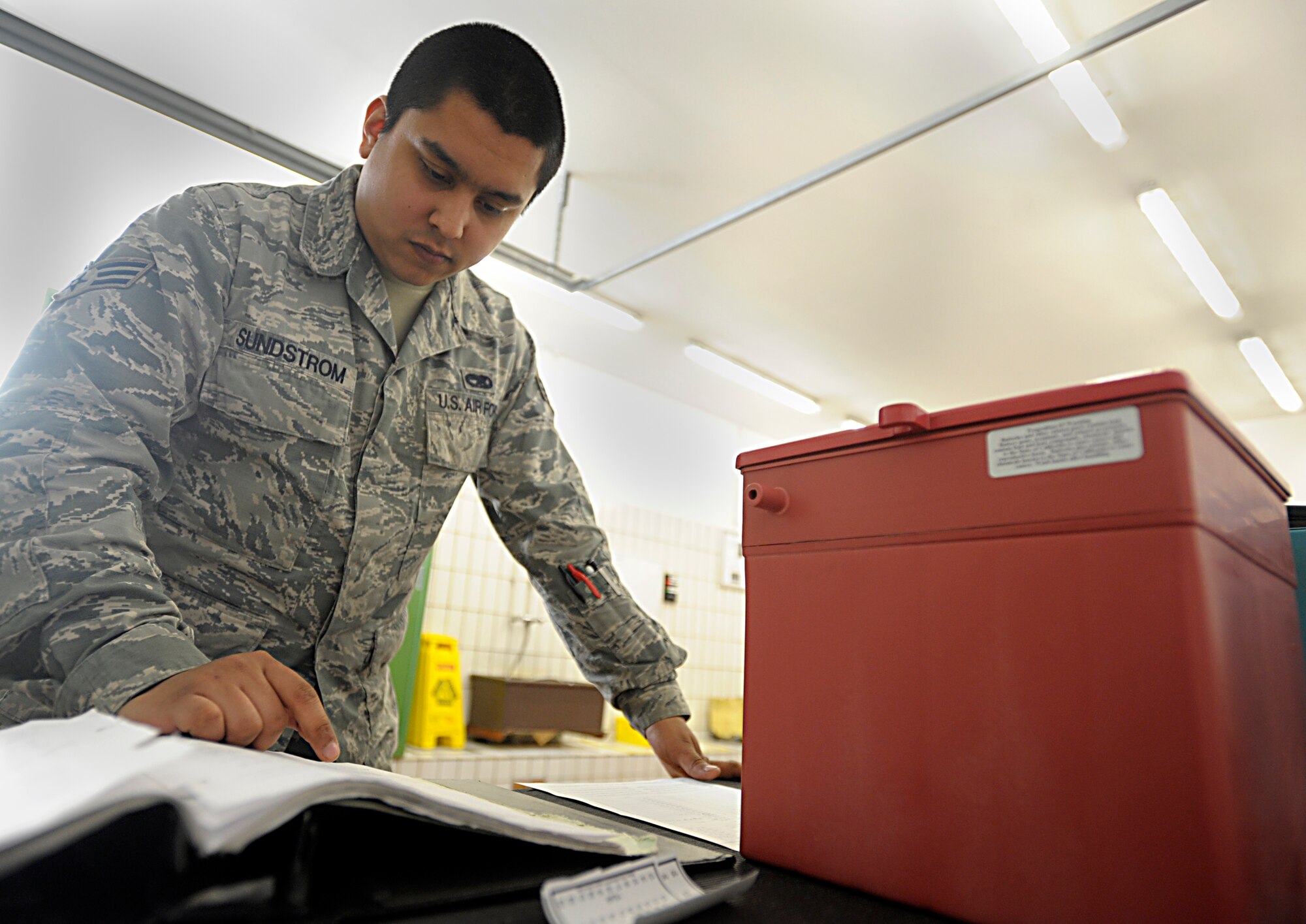 Senior Airman Gabriel Sundstrom, 86th Maintenance Squadron electrical and environmental specialist, looks over a technical order before inspecting a battery at Ramstein Air Base, Germany, Jan. 15, 2015. The electrical and environmental systems flight performs pre-flight and preventative maintenance on all aircraft and systems to keep them operational for mission readiness. (Senior Airman Timothy Moore/Released)