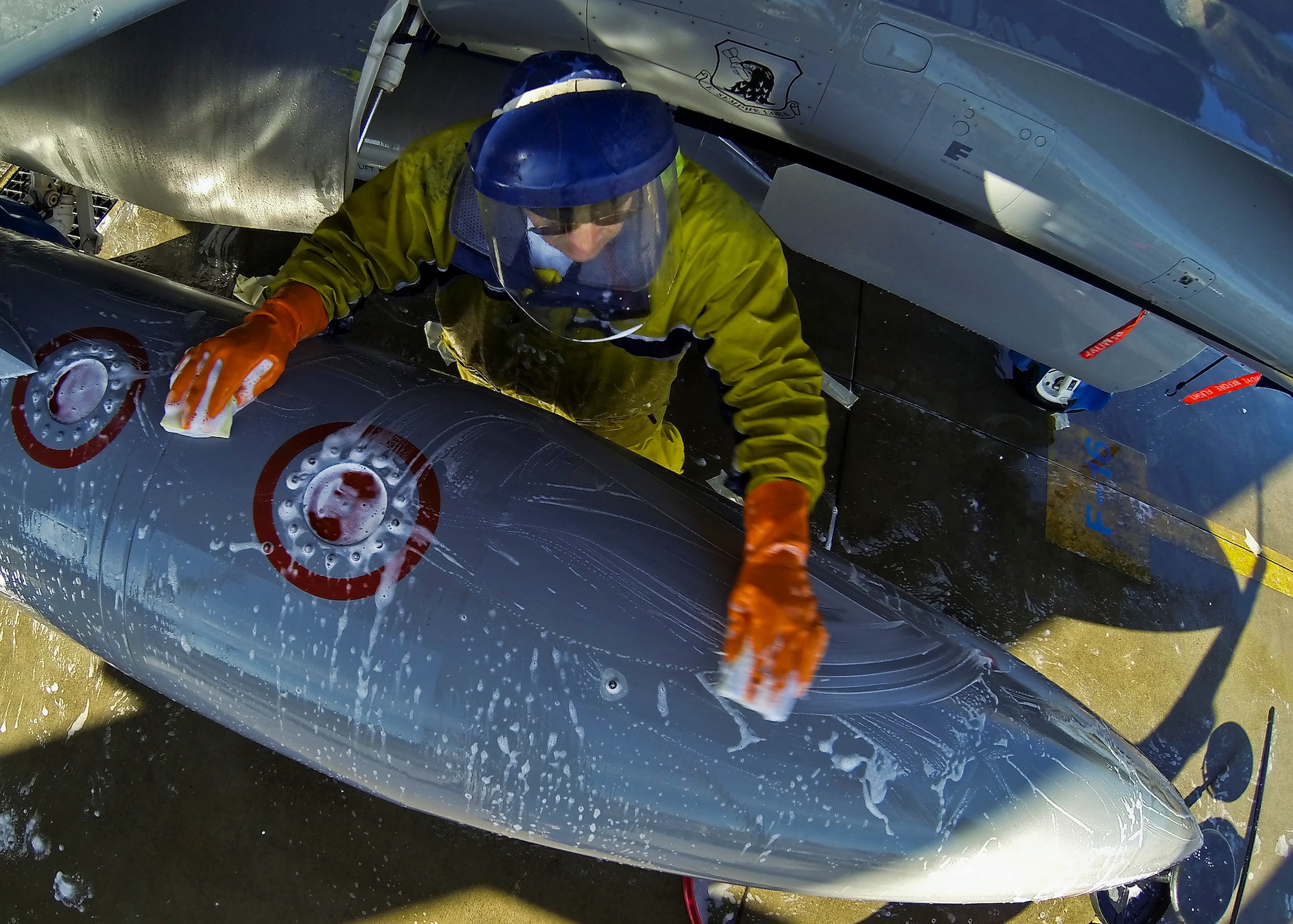 Jose Vega, a contractor with PAE, wipes down the external fuel cell of an F-16 Fighting Falcon at Eglin Air Force Base, Fla. PAE maintains the 96th Test Wing wash rack and also supports armament, engines, sheet metal, aero repair, metals tech, non-destructive inspection, aircraft phase dock and fuels repair shop. (U.S. Air Force photo/Samuel King Jr.)