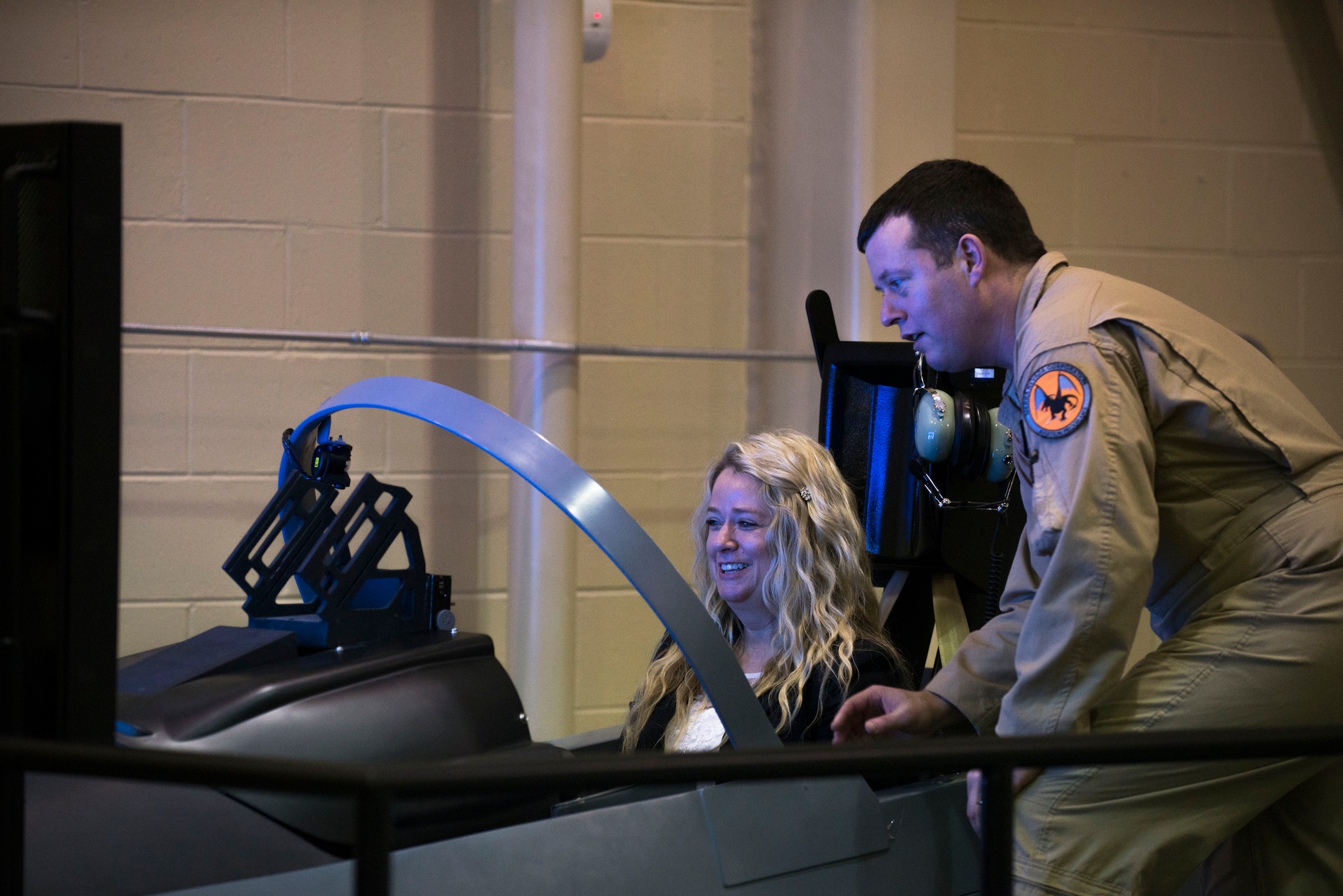 Chris Vander Sys, Sierra Nevada Corporation senior pilot, shows Michelle Nichols, wife of U.S. Air Force Col. John Nichols, 14th Fighter Wing commander, how to use an A-29 Super Tucano simulator Jan. 15, 2015, at Moody Air Force Base, Ga. Michelle and her husband visited Moody to attend the 81st Fighter Squadron’s reactivation ceremony. (U.S. Air Force photo by Airman 1st Class Dillian Bamman/Released)