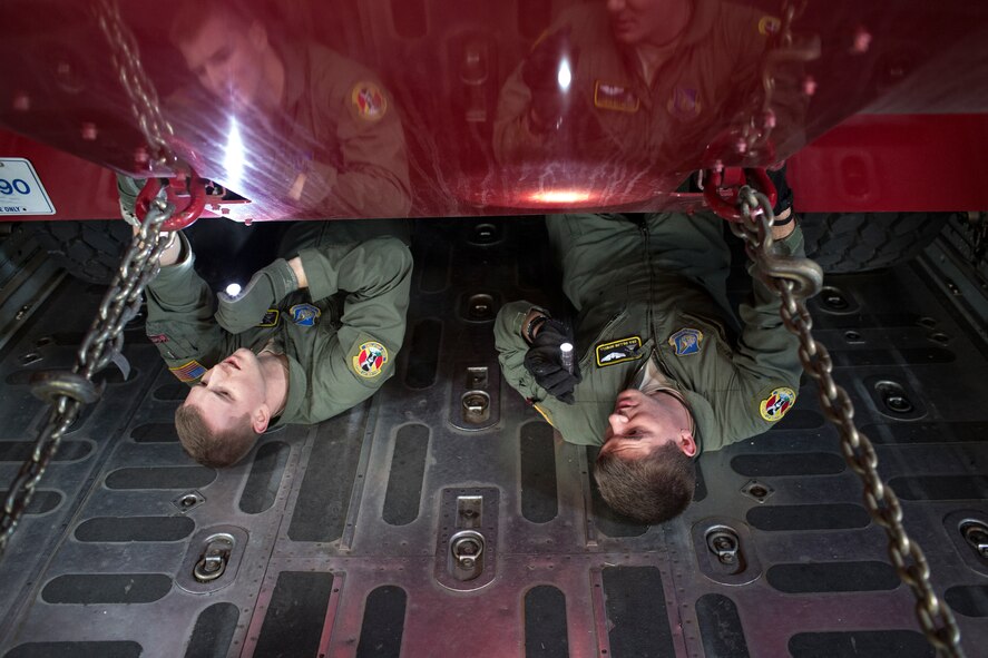 (Left to right) Senior Airman Christopher Hofer and Senior Airman Dillon Howell, both 36th Airlift Squadron loadmasters, inspect chains that secure a P-19 Aircraft Rescue Fire Fighting vehicle inside of a C-130 Hercules at Yokota Air Base, Japan, Jan. 14, 2015, during a Samurai Readiness Inspection. The readiness inspection was designed to evaluate areas such a rapid mobility response to simulated contingencies. (U.S. Air Force photo by Osakabe Yasuo/Released)