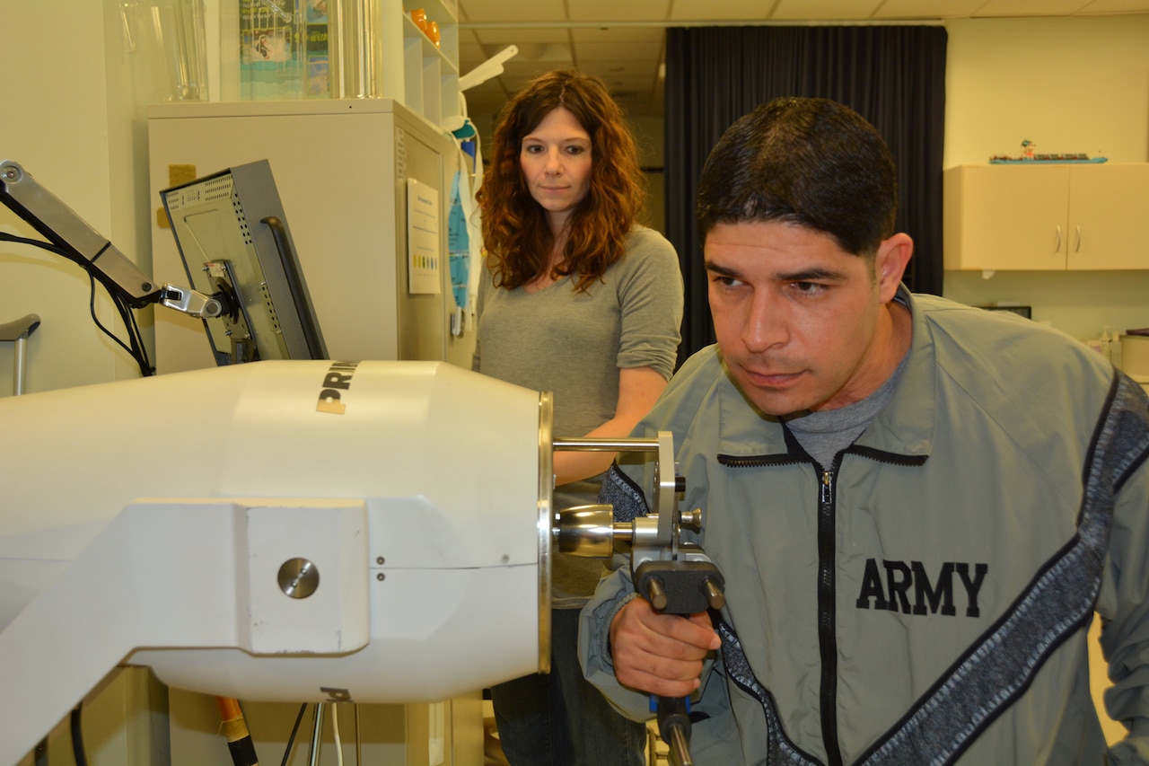 Army 1st Lt. John Arroyo works on strengthening his right hand while his occupational therapist, Katie Korp, looks on at the Center for the Intrepid, Brooke Army Medical Center’s rehabilitation facility at Joint Base San Antonio-Fort Sam Houston, Jan. 16, 2015. Arroyo, severely wounded in a shooting at Fort Hood, hopes his story of survival will inspire others. U.S. Army photo by Robert Shields