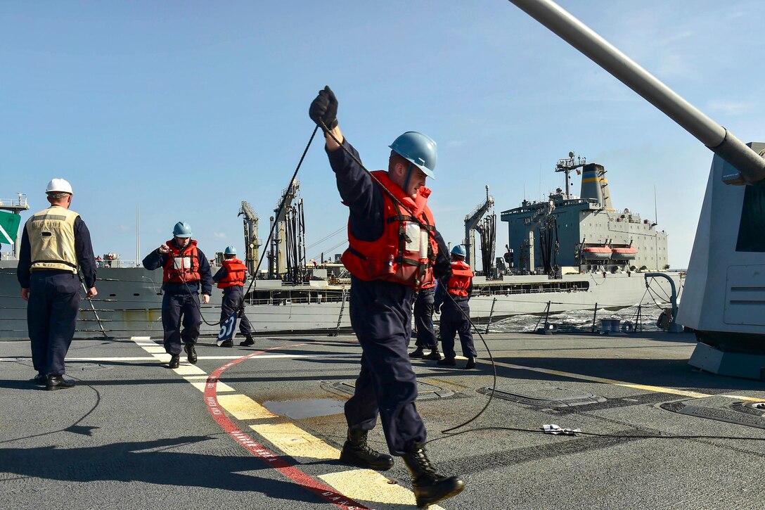 U.S. sailors haul in a phone and distance line on the deck of the