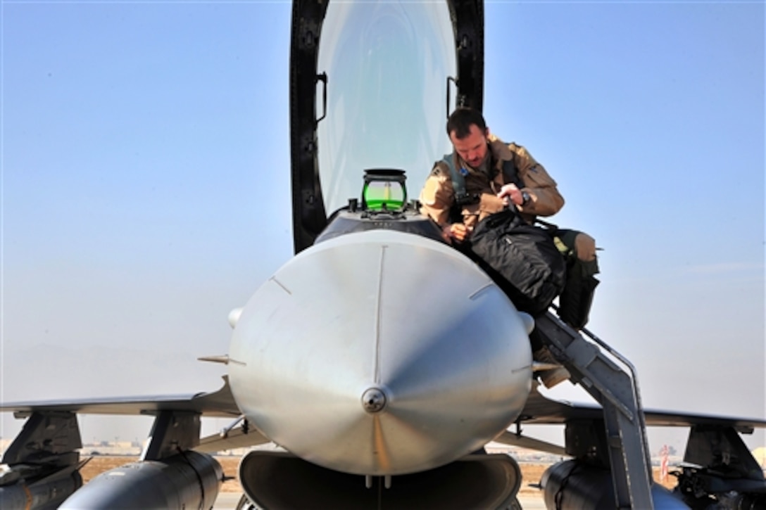 U.S. Air Force Capt. Shayne Carroll examines his gear before climbing into the cockpit of an F-16 Fighting Falcon aircraft for a mission on Bagram Air Field, Afghanistan, Jan. 9, 2015. Carroll is a pilot assigned to the 4th Expeditionary Fighter Squadron.