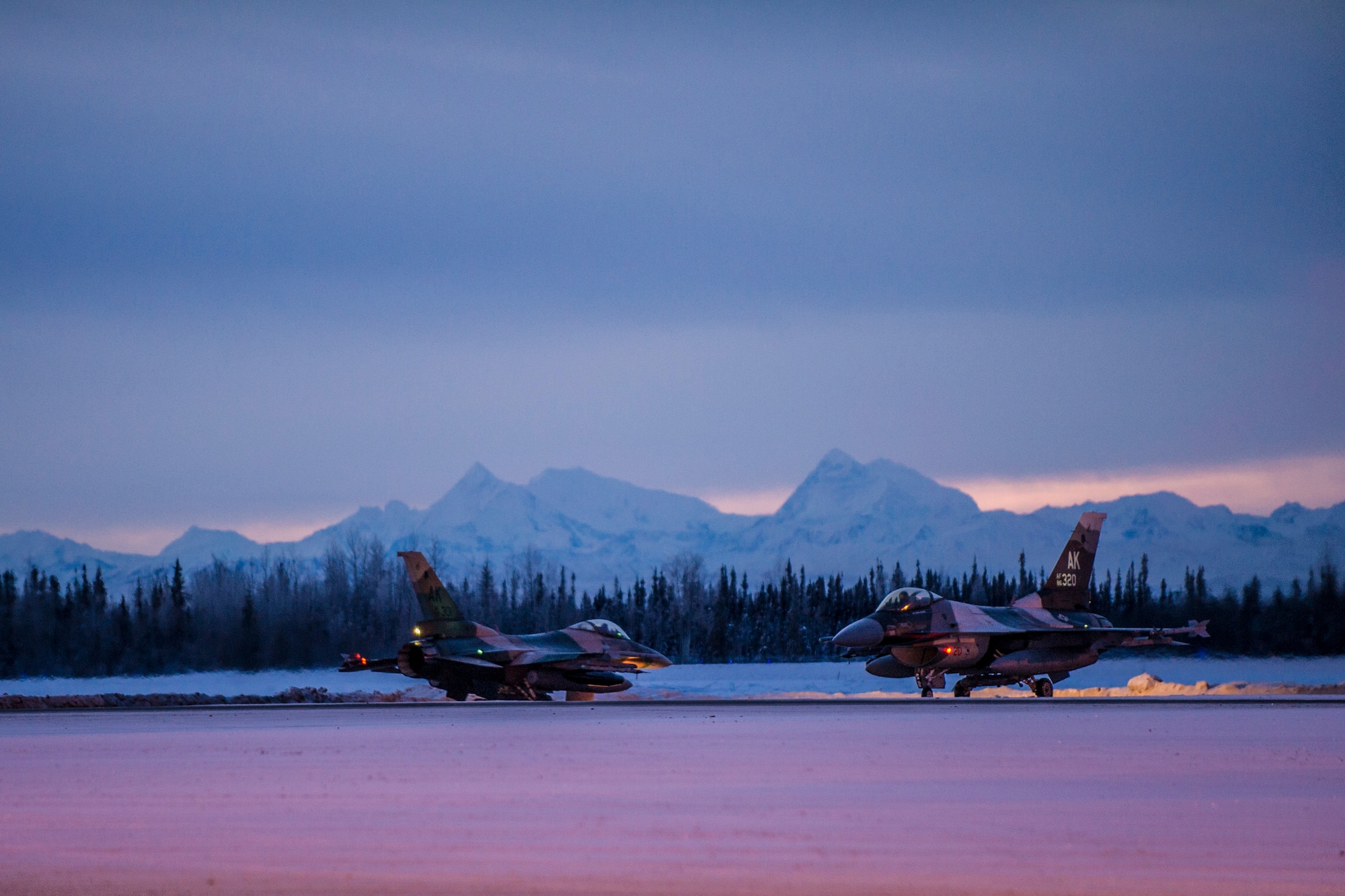 Two of 14 U.S. Air Force F-16 Fighting Falcon aircraft with the 18th Aggressor Squadron taxi at Eielson Air Force Base, Alaska, Jan. 17, 2015, for travel to Joint Base Pearl Harbor-Hickam, Hawaii, and Andersen Air Force Base, Guam, to participate in Pacific Air Forces exercises. More than 150 maintainers will keep the Aggressors in the air during the exercises, which are meant to prepare U.S. Airmen, Sailors and Marines along with coalition partners in the Pacific theater of operations for contingency operations if the need arises. (U.S. Air Force photo by Staff Sgt. Joshua Turner/Released)