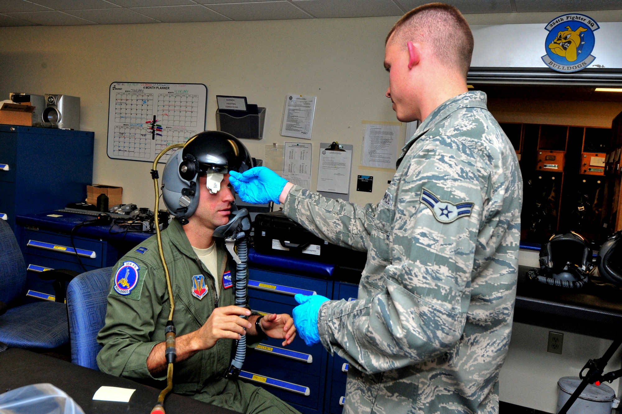 U.S. Air Force Capt. Ryan Van Bockel, 354th Fighter Squadron pilot, provides feedback about the fit of his helmet to Airman 1st Class Joseph Gago, 355th Operations Support Squadron Aircrew Flight Equipment technician, at Davis-Monthan Air Force Base, Ariz., Jan. 8, 2014.  Technicians from the 355th OSS AFE flight modified and refit each pilots' existing helmets to accommodate the new device. (U.S. Air Force photo by Airman 1st Class Chris Massey/Released)