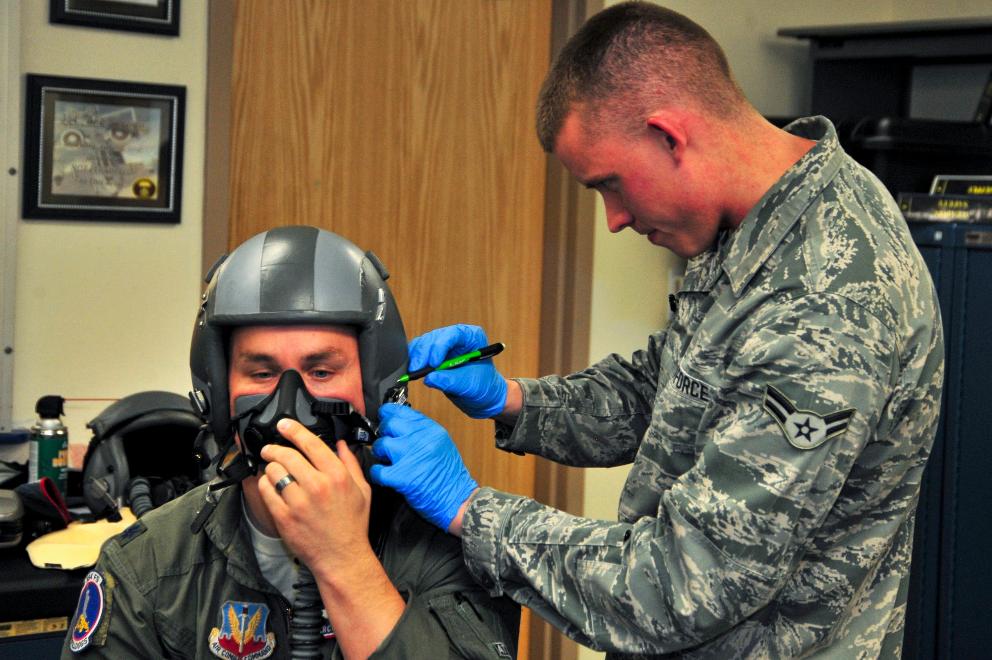 U.S. Air Force Lt. Col. Aaron Redfern, 354th Fighter Squadron director of operations, holds his mask in place while Airman 1st Class Joseph Gago, 355th Operations Support Squadron Aircrew Flight Equipment technician, marks a spot on Redfern's helmet to fit a new helmet mounted integrated targeting system at Davis-Monthan Air Force Base, Ariz., Jan. 8, 2014.  Technicians from the 355th OSS AFE flight modified and refit each pilots' existing helmets to accommodate the new device. (U.S. Air Force photo by Airman 1st Class Chris Massey/Released)