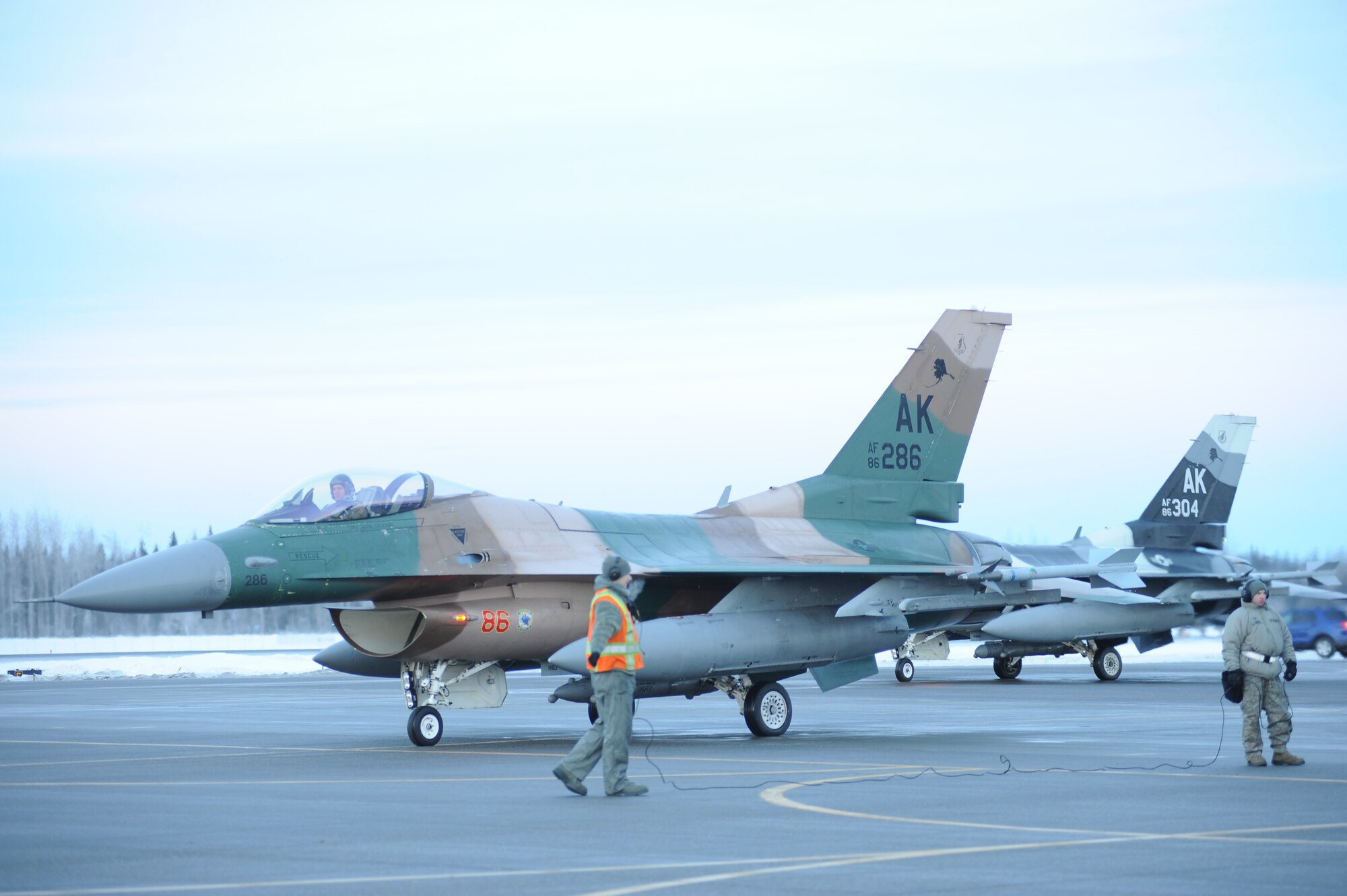 Airmen assigned to the 354th Maintenance Group prepare F-16 Fighting Falcon aircraft assigned to the 18th Aggressor Squadron for take-off from Eielson Air Force Base, Alaska, Jan. 17, 2015. The jets are in transit to Joint Base Pearl Harbor-Hickam, Hawaii, and Andersen Air Force Base, Guam, to participate in Pacific Air Forces exercises. More than 150 maintenance Airmen will keep the Aggressors in the air during the exercises which are meant to prepare U.S. Airmen, Sailors and Marines along with coalition partners in the Pacific theater of operations for contingency operations if the need arises. (U.S. Air Force photo by Staff Sgt. Kirsten Wicker/Released) 