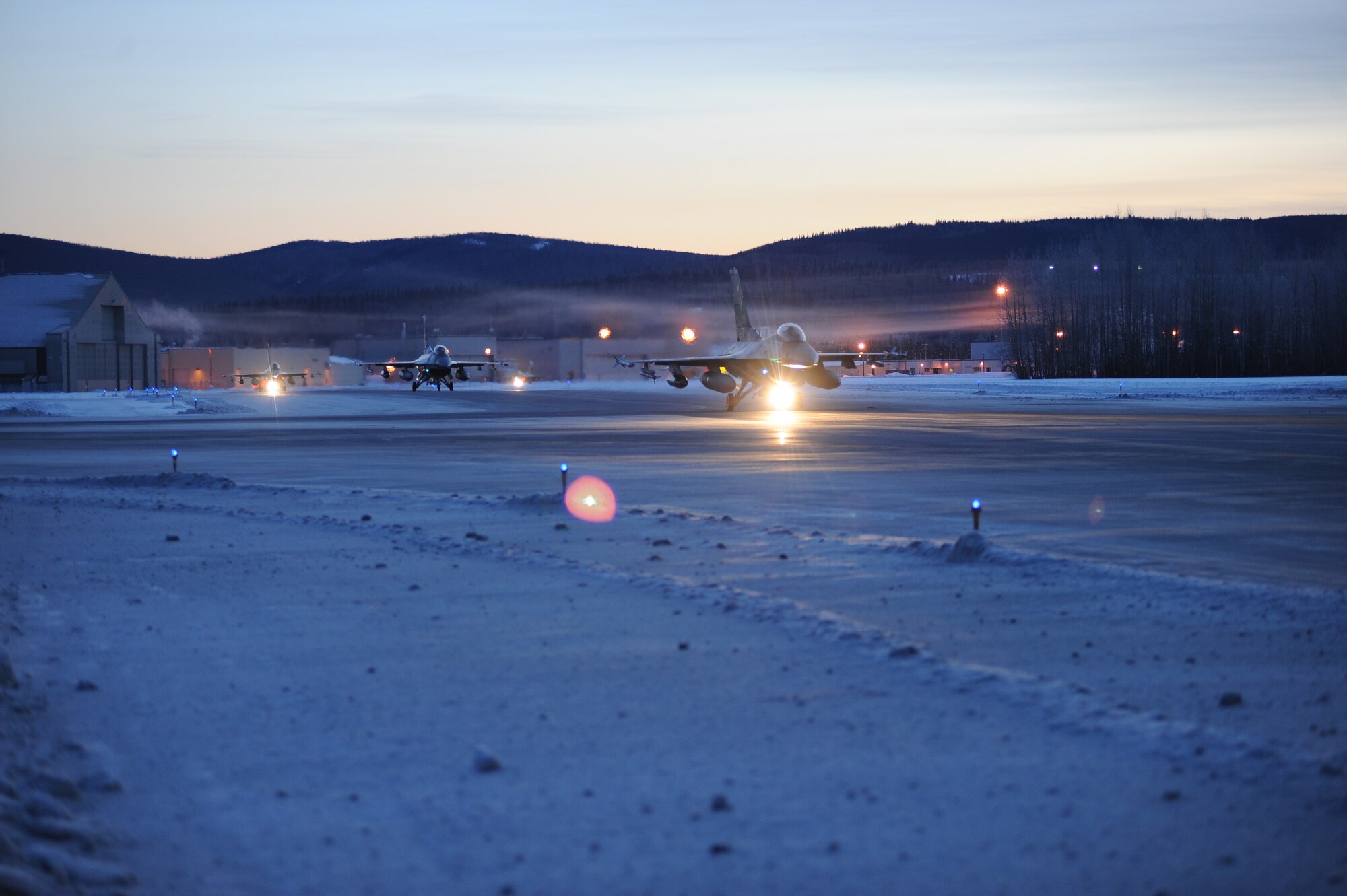 Three of 14 U.S. Air Force F-16 Fighting Falcon aircraft assigned to the 18th Aggressor Squadron taxi to the runway before take-off from Eielson Air Force Base, Alaska, Jan. 17, 2015. The jets are in transit to Joint Base Pearl Harbor-Hickam, Hawaii, and Andersen Air Force Base, Guam, to participate in Pacific Air Forces exercises. More than 150 maintenance Airmen will keep the Aggressors in the air during the exercises which are meant to prepare U.S. Airmen, Sailors and Marines along with coalition partners in the Pacific theater of operations for contingency operations if the need arises. (U.S. Air Force photo by Staff Sgt. Kirsten Wicker/Released)