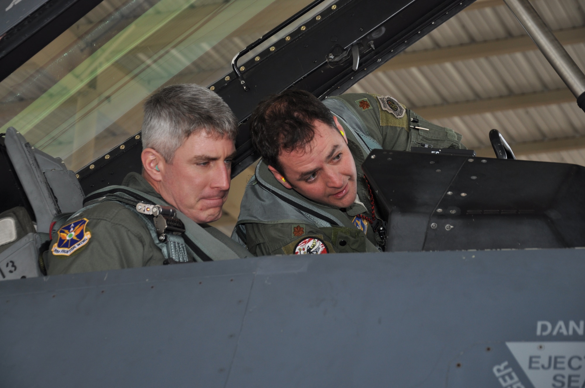 NAVAL AIR STATION FORT WORTH JOINT RESERVE BASE, Texas - Air Force Maj. Christopher Zorich, a 457th Fighter Squadron pilot, instructs Navy Captain Gil Miller, the installation commanding officer, in a F-16 before a familiarization flight here Jan. 14, 2015. Although the Skipper has logged over 4,700 hours in various aircraft, this was his first time in a F-16. NAS Fort Worth JRB recently celebrated 20 years as a joint installation. (U.S. Air Force photo/Master Sgt. Julie Briden-Garcia)
