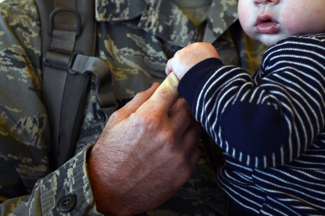 U.S. Air Force Staff Sgt. Aaron Ryder, 7th Civil Engineer Squadron electrician, has his finger held by his son, Colt, Jan. 8, 2015, in Abilene, Texas. More than 30 Dyess Airmen spent time with their families at Abilene Regional Airport before departing in support of deployed operations. (U.S. Air Force photo by Airman 1st Class Kedesha Pennant/Released)