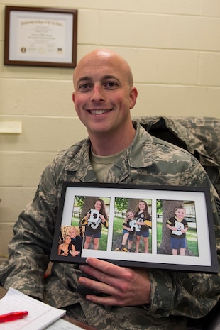 Staff Sgt. Shawn Nyer holds up photos of his family, Jan. 13, 2015 at Joint Base Charleston, S.C. Nyer is the 437th Operations Support Squadron Aircrew Flight Equipment NCO in charge of the Aviator Helmet and Mask section. (U.S. Air Force photo/ Senior Airman Jared Trimarchi) 