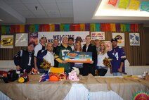 (Center and to the right) Holding a commemorative poster, 2nd Lt. Christopher Elworth is joined by 319th Air Base Wing commander Col. Paul Bauman, Minnesota Vikings Cheerleaders and Super Base Extravaganza officials and guests for a group photo after winning the Super Base Extravaganza bingo grand prize of a trip to Super Bowl XLIX Jan. 17, 2015, at the Northern Lights Club at Grand Forks Air Force Base, N.D. Super Base  Extravaganza, formerly known as Super Bowl Extravaganza and more commonly referred to as  SBE, is the base’s largest annual fundraiser. (U.S. Air Force photo/Staff Sgt. Luis Loza Gutierrez)