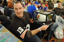 Maj. Frank Burks holds up the Jim Brown autographed football he won in an auction at the Super Base Extravaganza, Jan. 17, 2015, at the Northern Lights Club on Grand Forks Air Force Base, N.D. Items autographed by National Football League greats such as Cleveland Brown running back, Jim Brown, and San Francisco 49ers wide receiver, Jerry Rice, were among the dozens of authentic sports memorabilia auctioned and raffled at this year’s SBE. (U.S. Air Force photo/Staff Sgt. Luis Loza Gutierrez)
