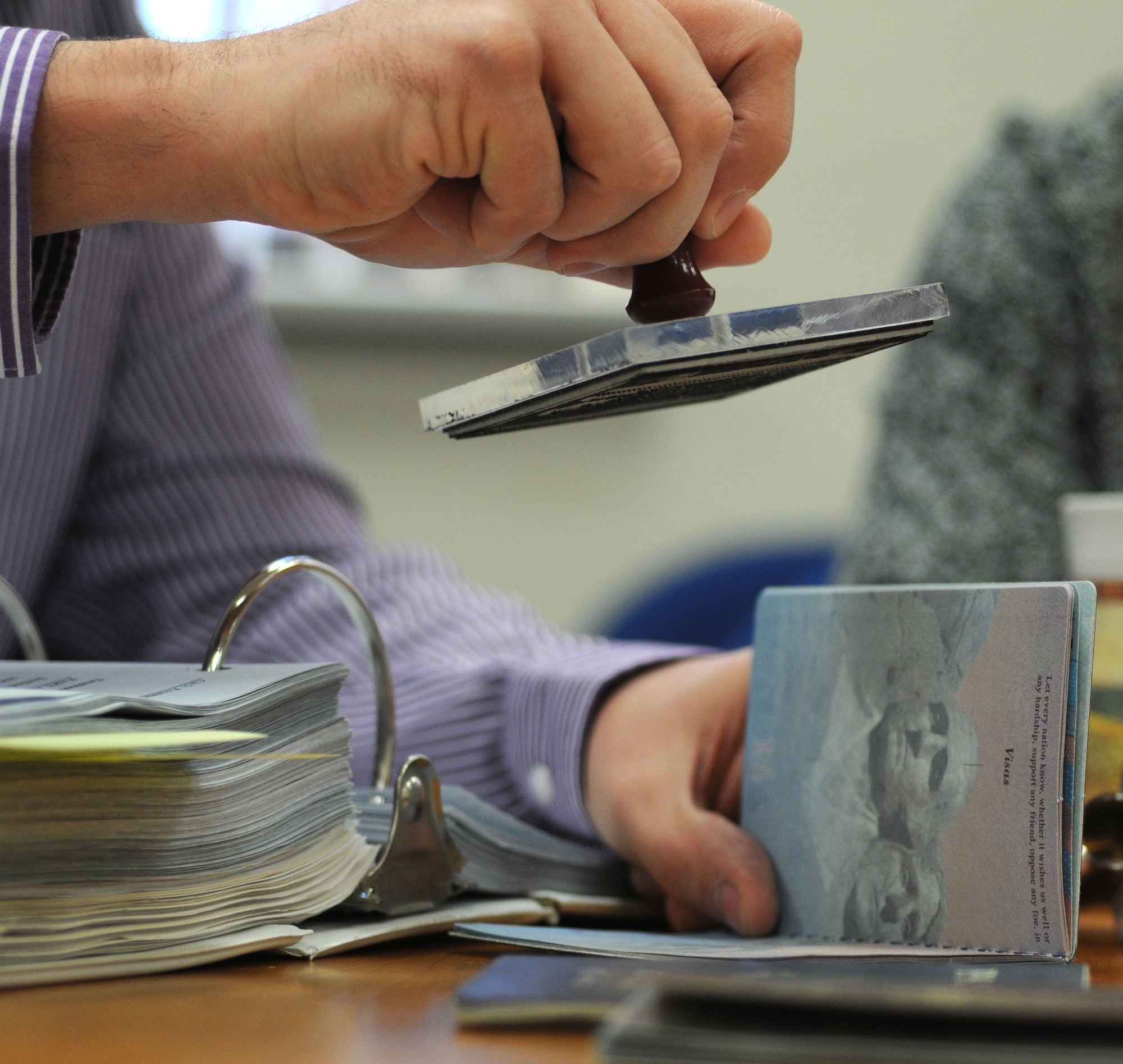 Richard Ribardo, 100th Force Support Squadron Civilian Personnel Office human resources specialist from Lakenheath, Suffolk, stamps an official passport Dec. 31, 2014, on RAF Mildenhall, England. The CPO has to identify people who work for the Department of Defense in their passports so they can receive certain tax exemptions. For example, if a civilian goes to buy a tax-free vehicle they must take their passport containing the issued stamp. (U.S. Air Force photo by Gina Randall/Released)