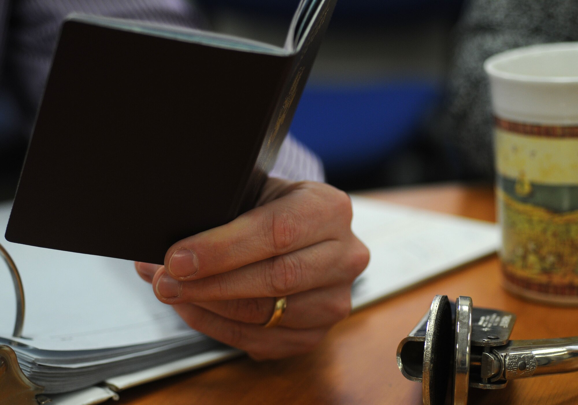 Richard Ribardo, 100th Force Support Squadron Civilian Personnel Office human resources specialist from Lakenheath, Suffolk, checks an official passport Dec. 31, 2014, on RAF Mildenhall, England. Every Department of Defense employee in England has to come through the CPO for passports. (U.S. Air Force photo by Gina Randall/Released)