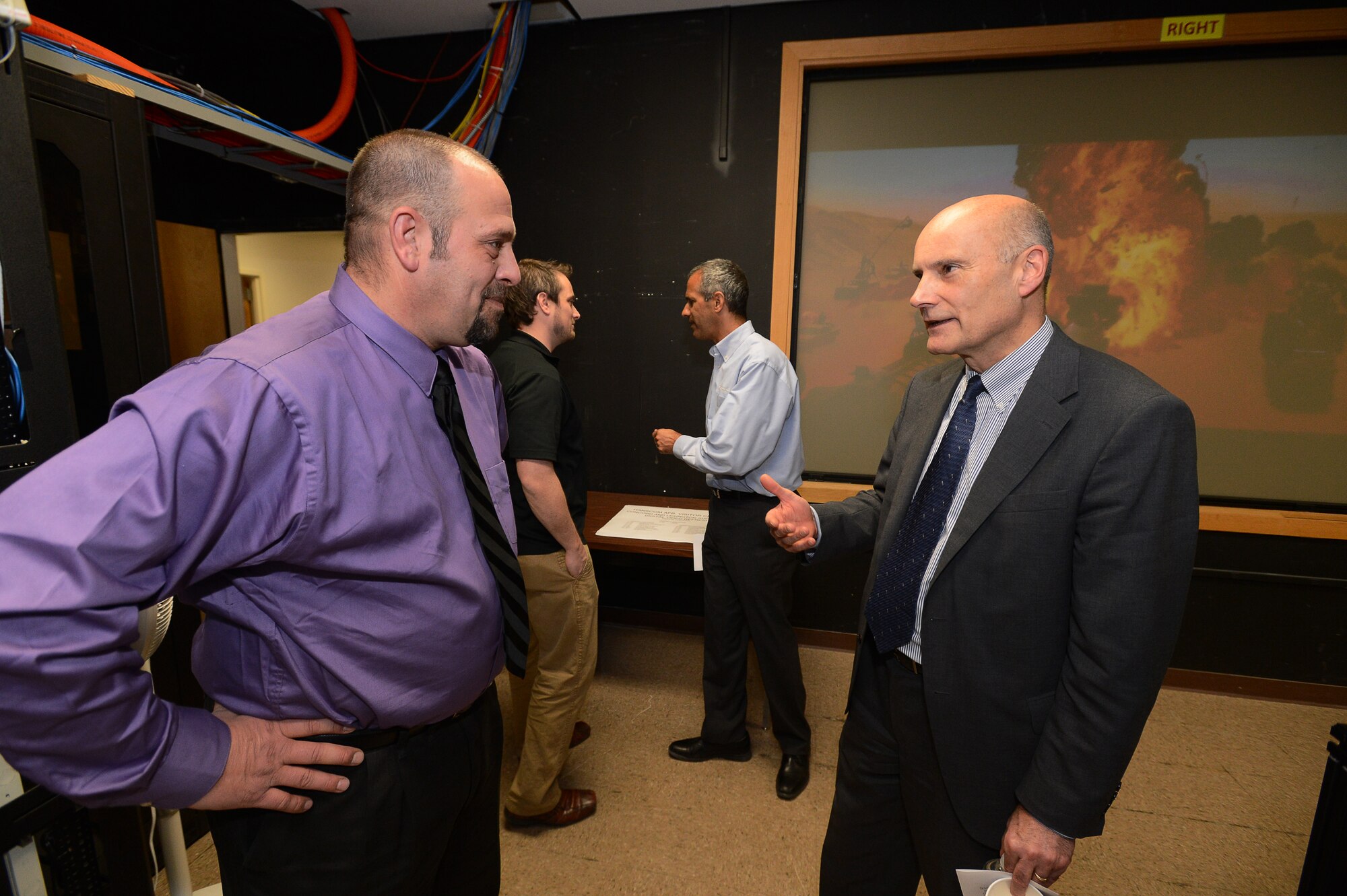 Tom Powis, C3I and Networks Directorate program management organizational senior functional, and Patrick Libby, 66th Communications and Information Division network engineer, discuss upgrades made to the Hanscom Conference Center during the official grand opening Jan. 20. A $500,000 upgrade to the audio visual equipment in the conference center's two largest and most frequently used meeting rooms, Lexington Amphitheater and Concord Room, was completed last month.  (U.S. Air Force photo by Jerry Saslav)