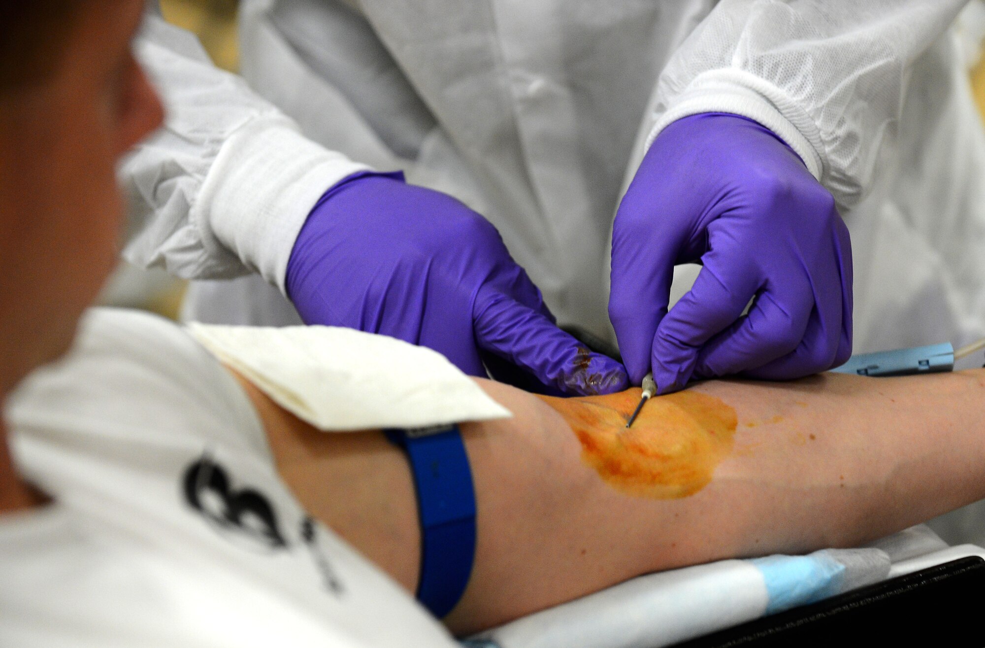 A Landstuhl Regional Medical Center laboratory technician inserts an intravenous line into a donor’s arm at the Brick House in the community center during the Armed Services Blood Program blood drive at Spangdahlem Air Base, Germany, Jan. 20, 2015. Donors were provided with drinks and food during their 15 minute recuperation time after donating one pint of their blood. (U.S. Air Force photo by Airman 1st Class Luke Kitterman/Released)

