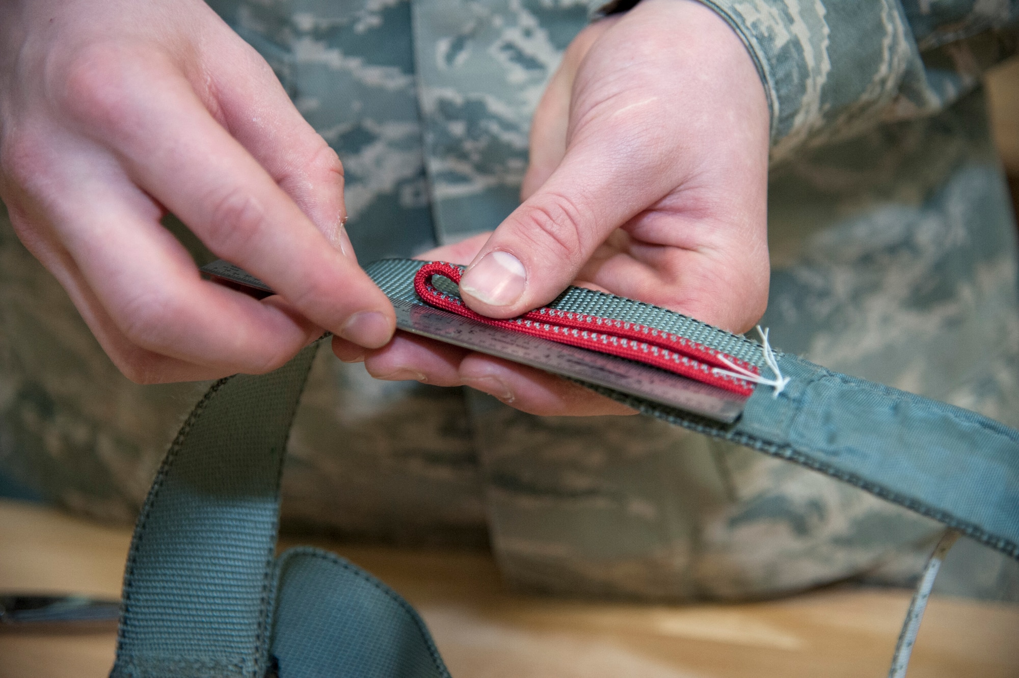 Senior Airman Mark Peterson, 51st Operations Support Squadron aircrew flight equipment journeyman, measures the length of the four line lanyard at Osan Air Base, Republic of Korea, Jan. 20, 2015. Each part of the parachute requires to be at certain meaurement to ensure it deploys properly. (U.S. Air Force photo by Senior Airman Matthew Lancaster)