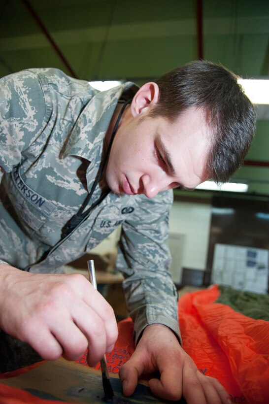 Senior Airman Mark Peterson, 51st Operations Support Squadron aircrew flight equipment journeyman, paints the date of installation onto a parachute at Osan Air Base, Republic of Korea, Jan. 20, 2015. This date is used a referance for when the parachute was first put into service. (U.S. Air Force photo by Senior Airman Matthew Lancaster)