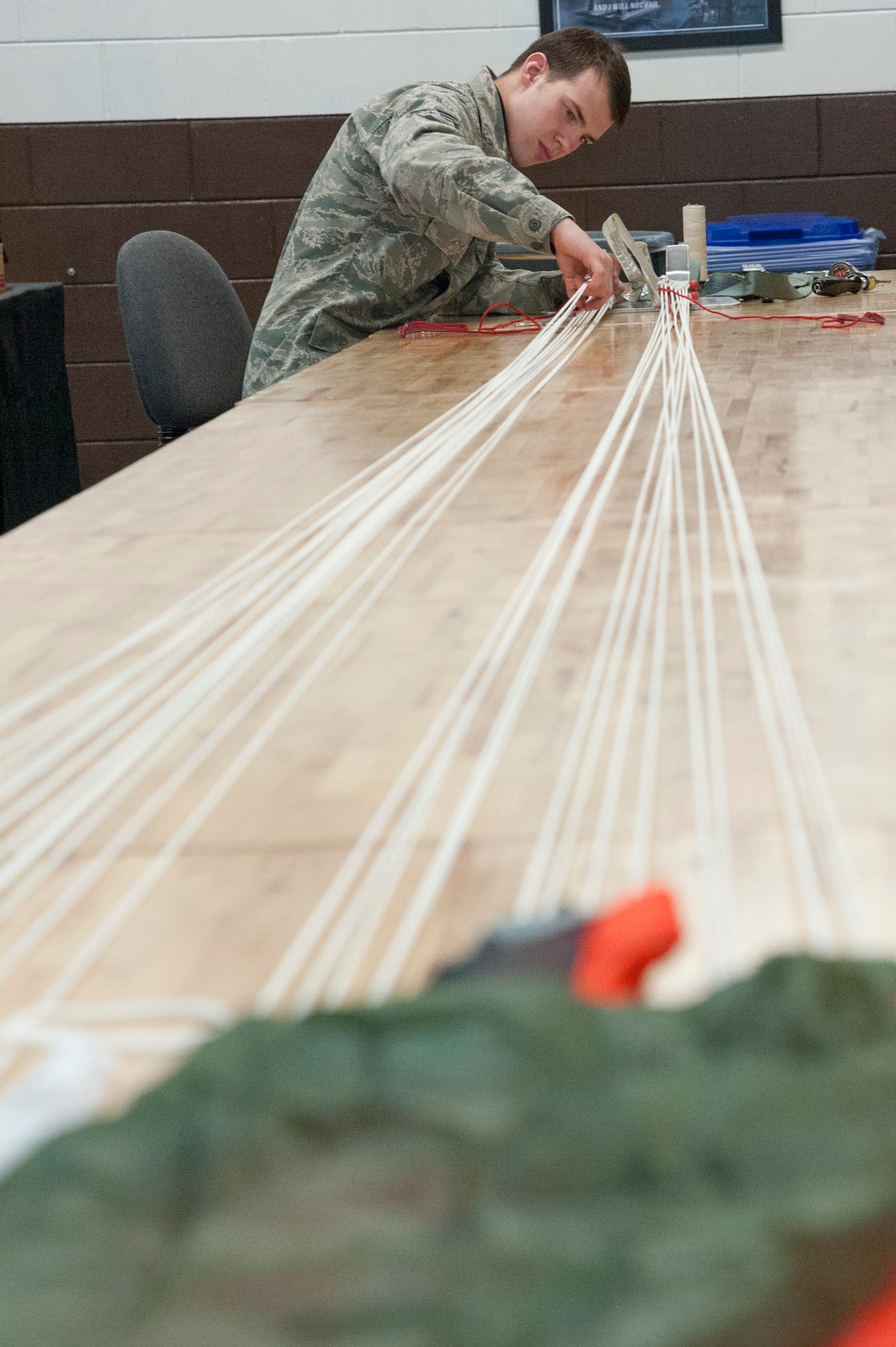 Senior Airman Mark Peterson, 51st Operations Support Squadron aircrew flight equipment journeyman, attaches a four line release lanyard onto a parachute at Osan Air Base, Republic of Korea, Jan. 20, 2015. The four line lanyards are used to help ster the parachute as well as relese air from the canopy. (U.S. Air Force photo by Senior Airman Matthew Lancaster)